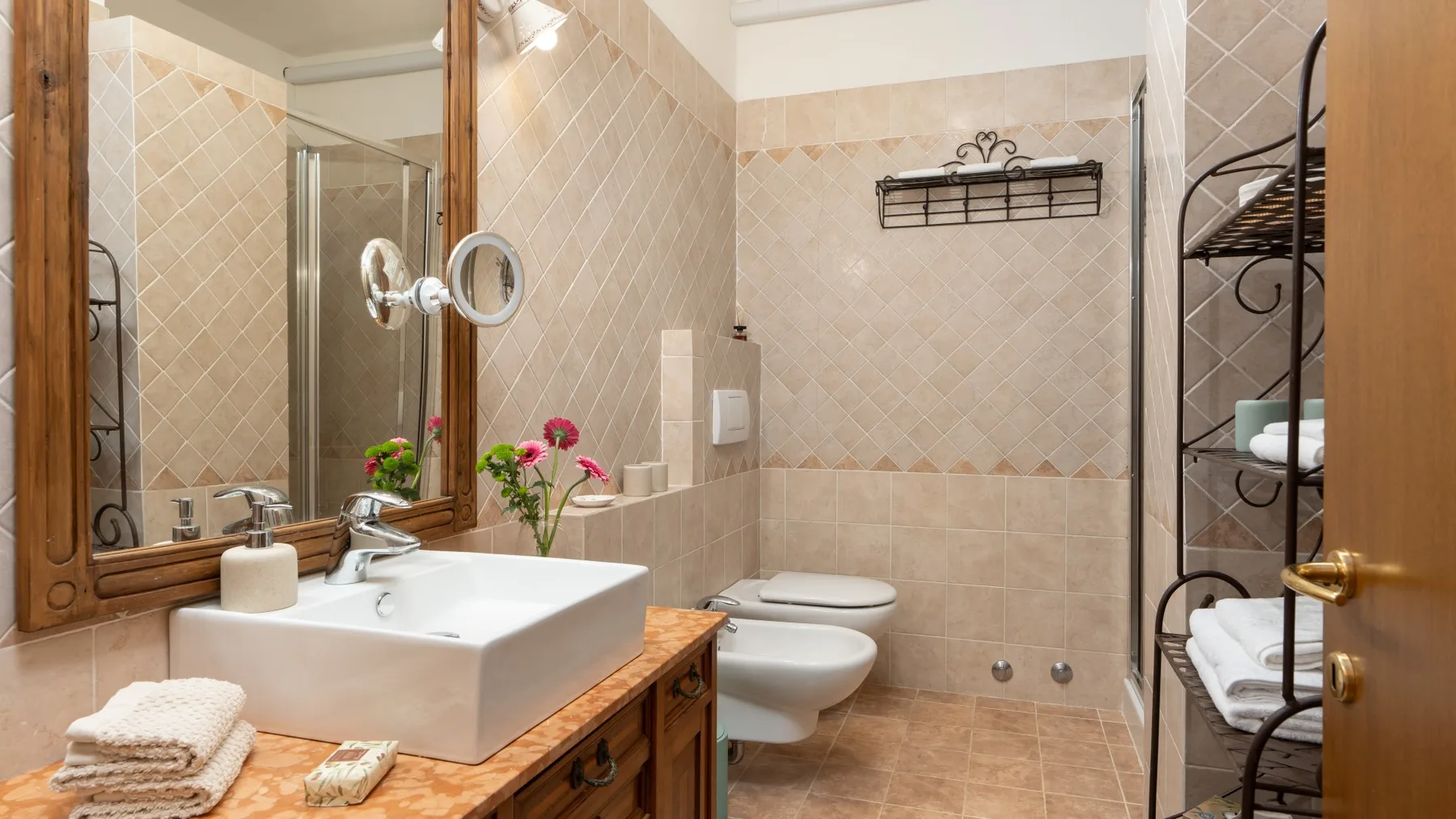 Un baño alicatado con lavabo, inodoro y ducha con mampara de vidrio.