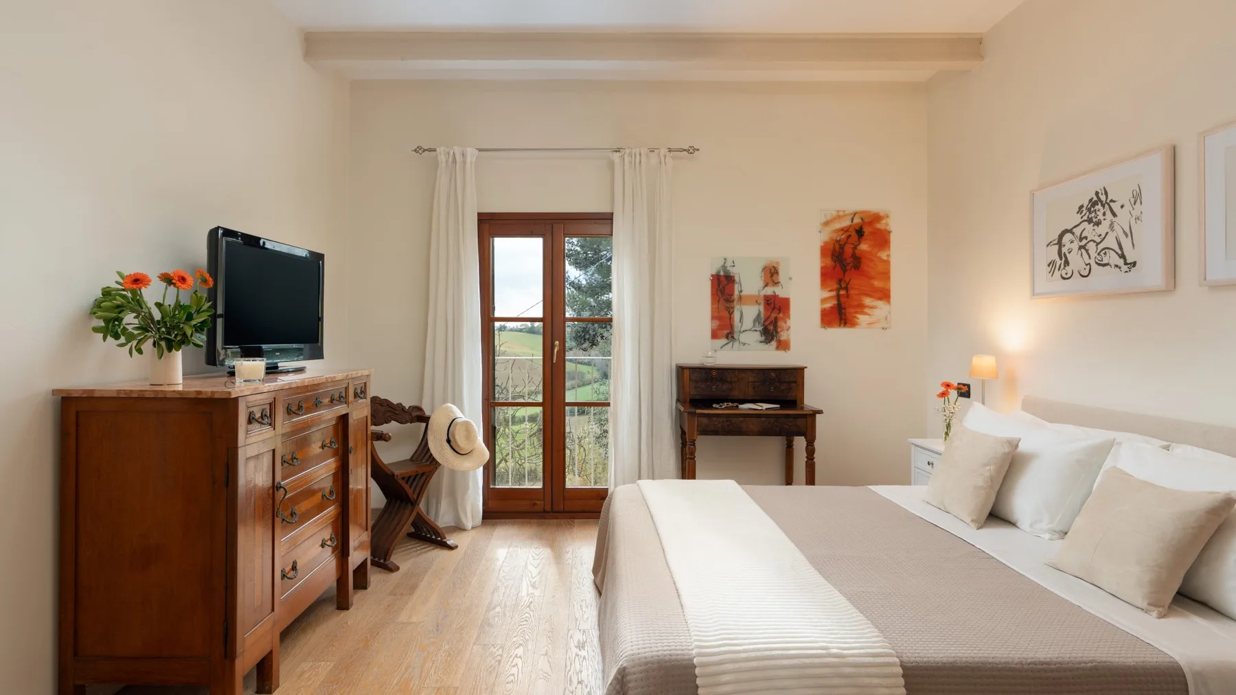 Un dormitorio con cama, cómoda de madera y puertas acristaladas que dan a un balcón.