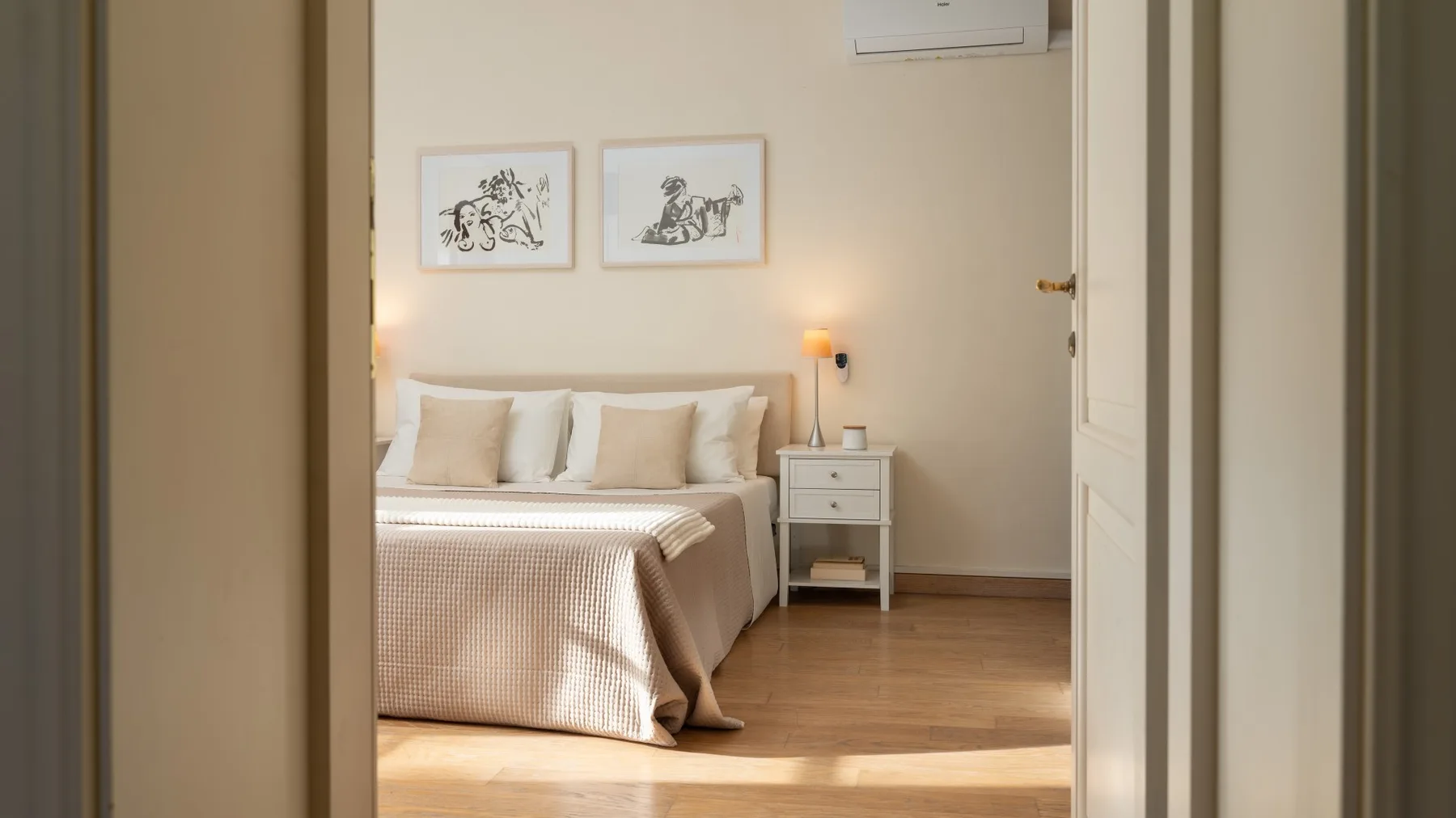 Un dormitorio con una cama bien tendida y obras enmarcadas encima.