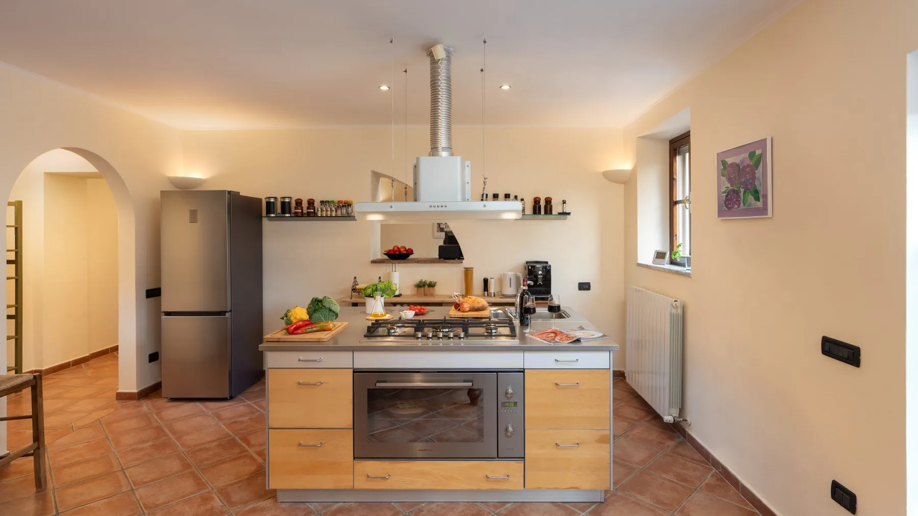 Una cocina luminosa con una isla central, una cocina y electrodomésticos de acero inoxidable.
