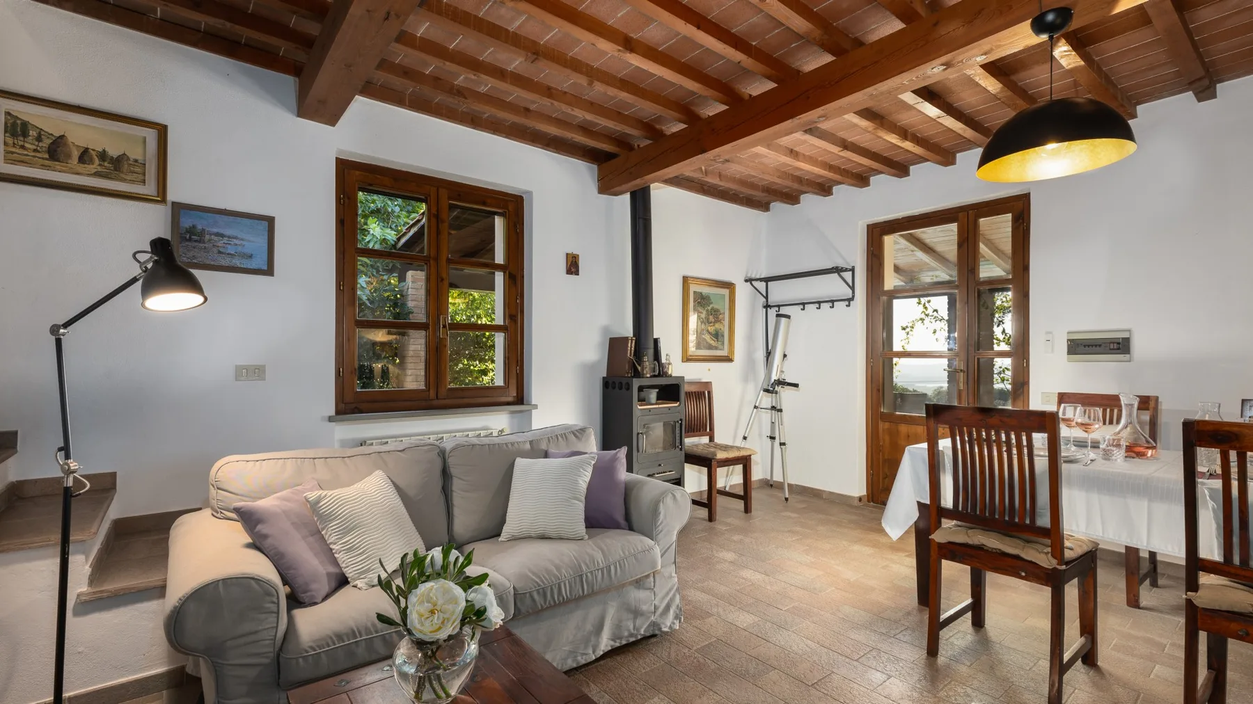 Una zona de estar y comedor con asientos bajo un techo con vigas de madera.