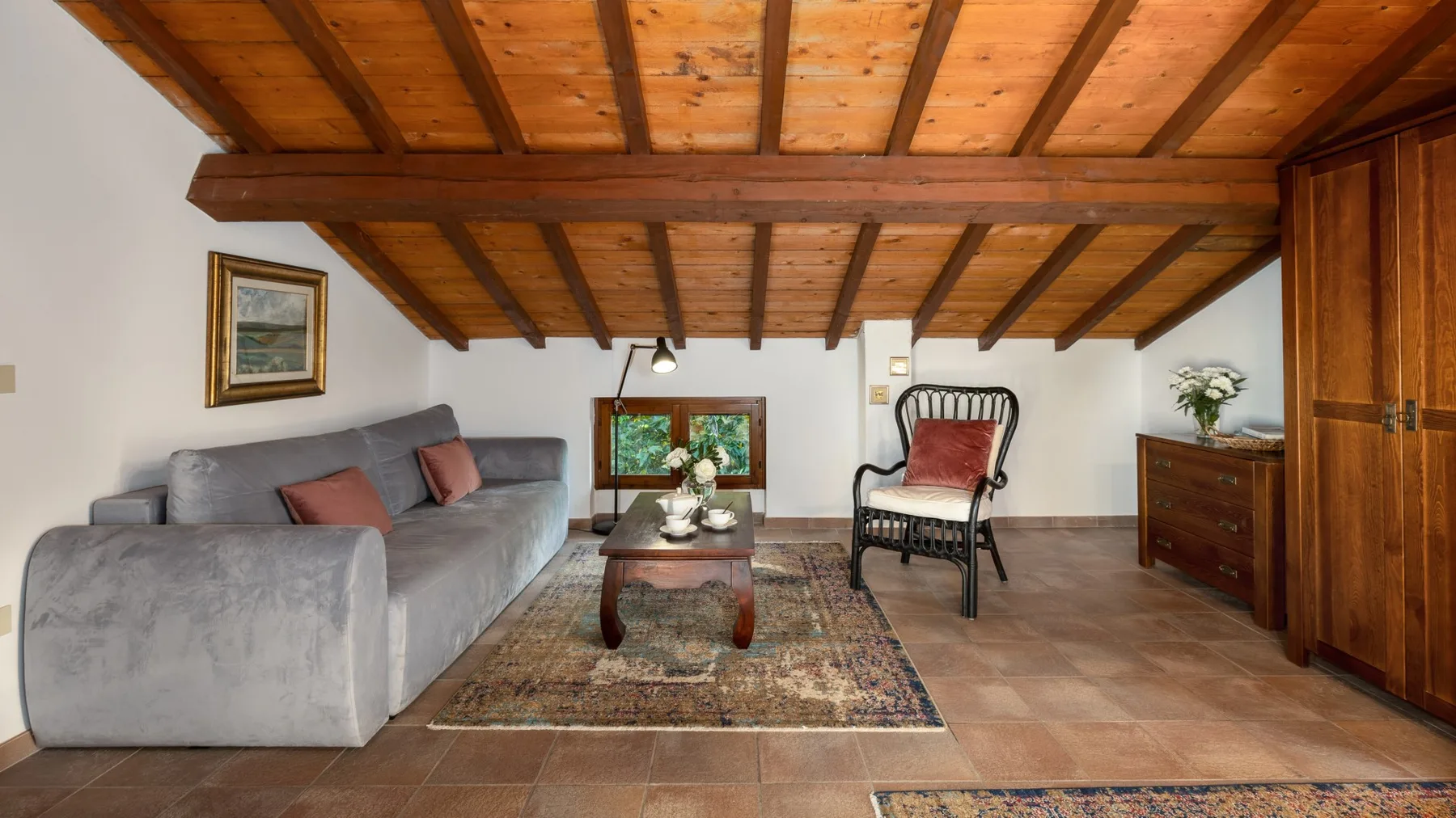 Una sala de estar con asientos alrededor de una mesa de centro bajo vigas de madera vistas.