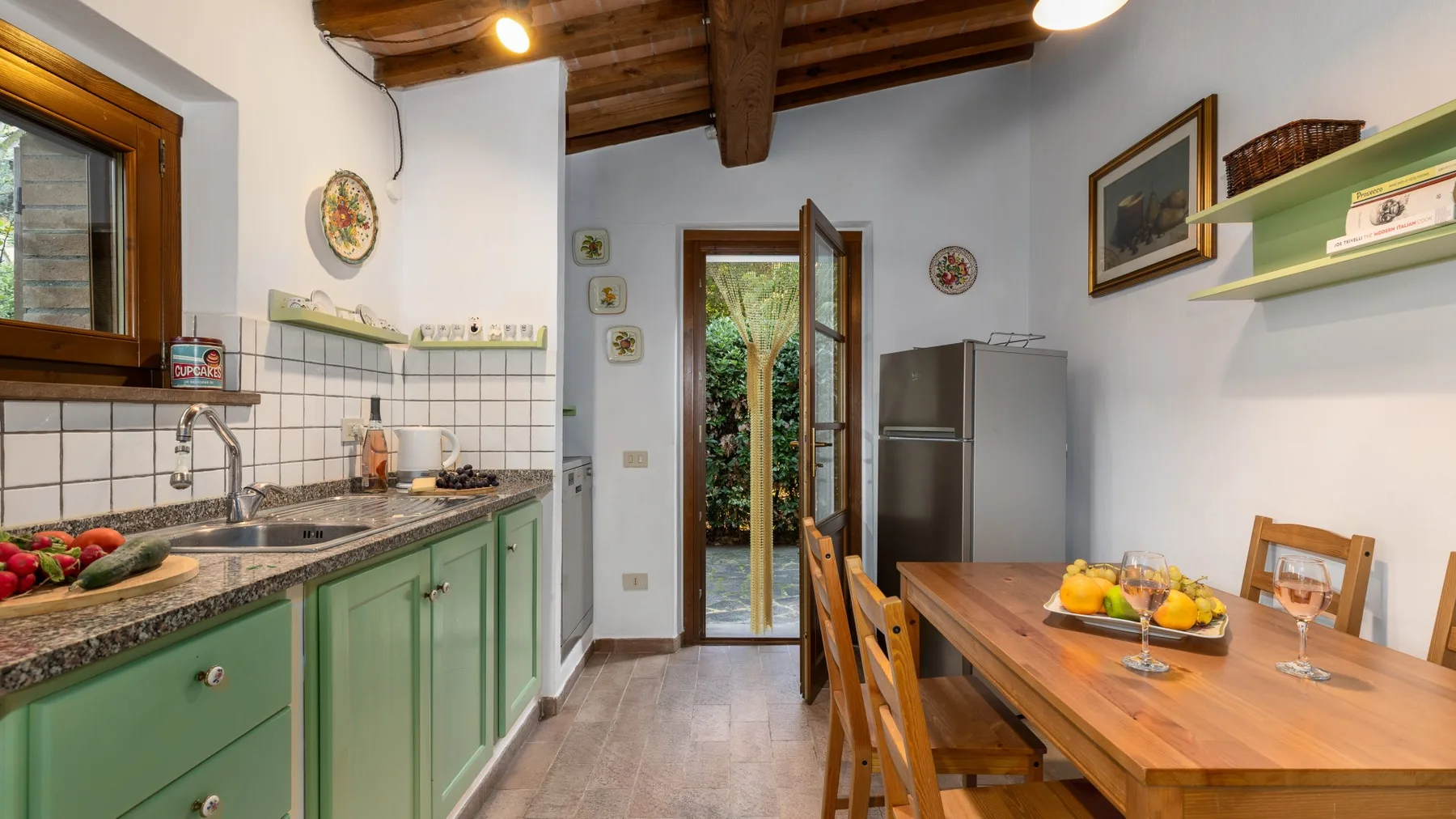Una cocina y comedor con gabinetes verdes y una mesa de madera.