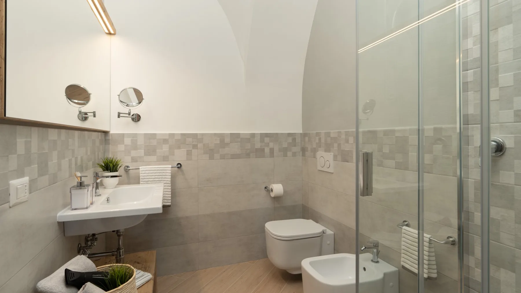 A bright bathroom with a wall-mounted sink and glass shower.