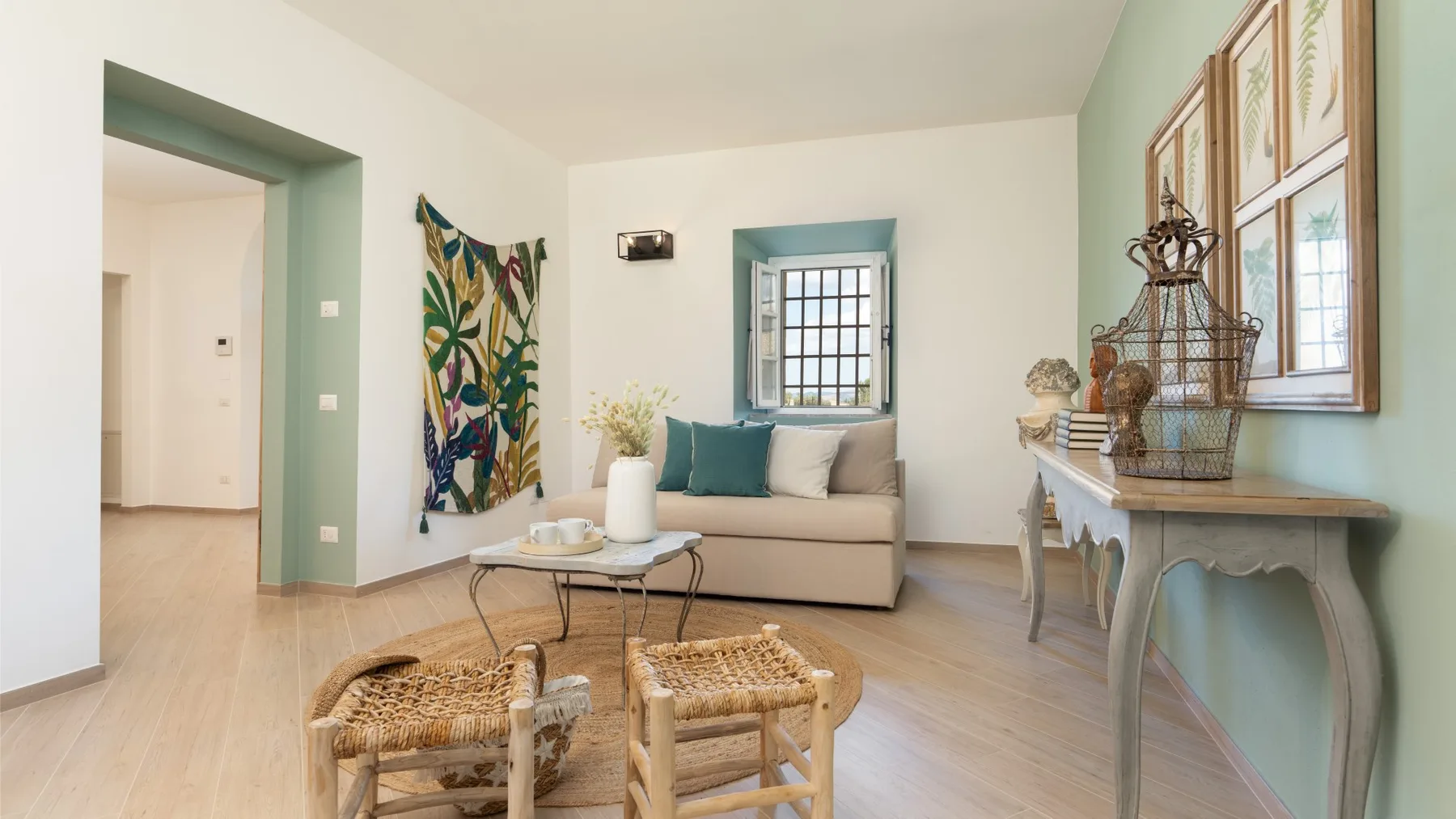 A bright living room with a sofa, a small table, and woven seating.