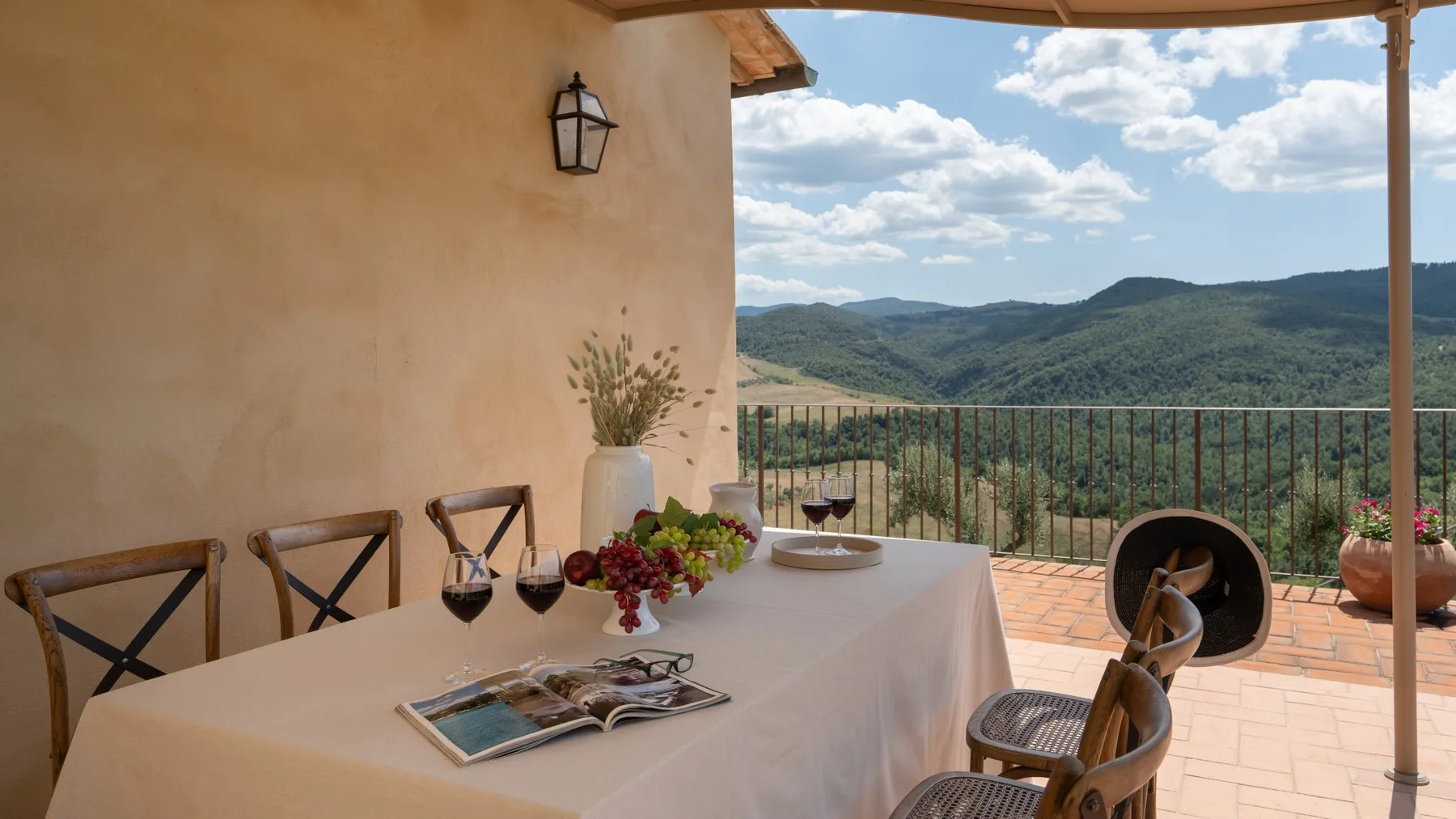 A covered outdoor dining area overlooks green hills and a partly cloudy sky.