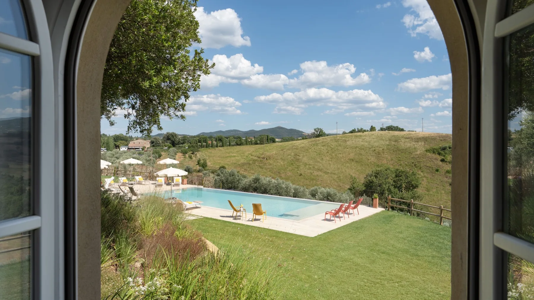 An outdoor swimming pool and grassy lawn sit beside open countryside.