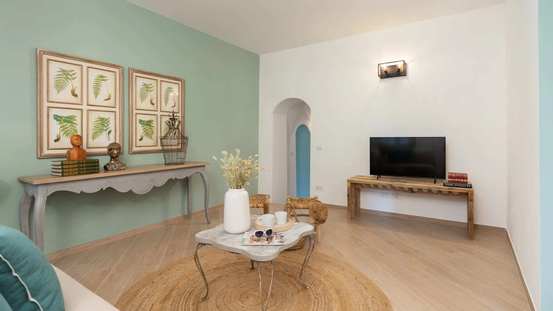 A living room with a television, a low table, and framed botanical prints.
