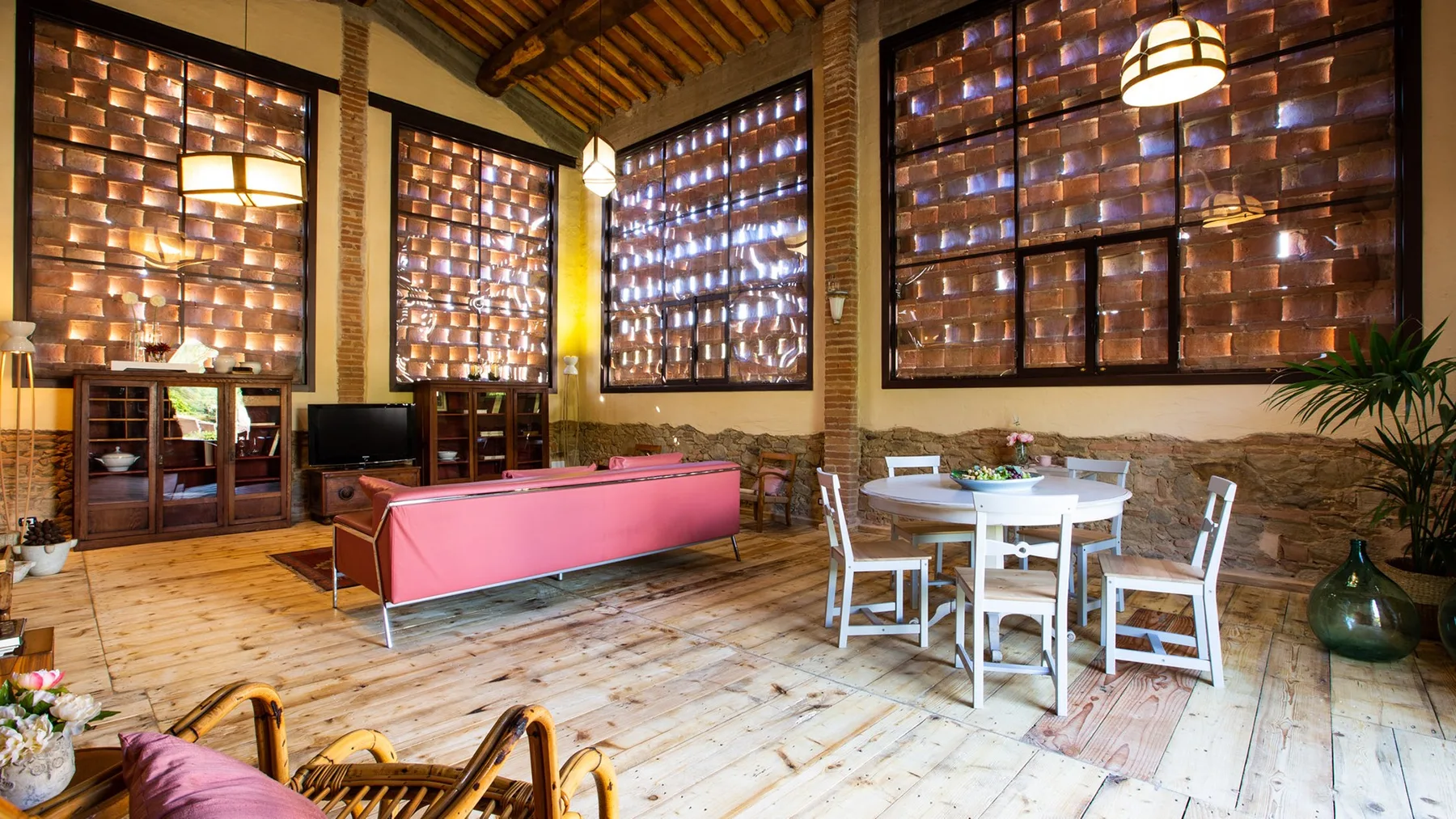 A bright rustic room with a pink pool table and a white dining set.