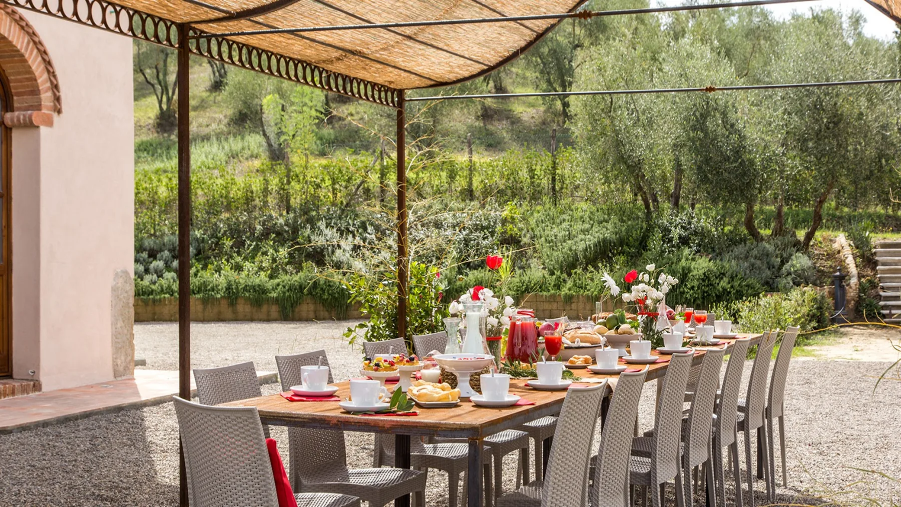 An outdoor dining area beneath a canopy, with a long table set for a meal.