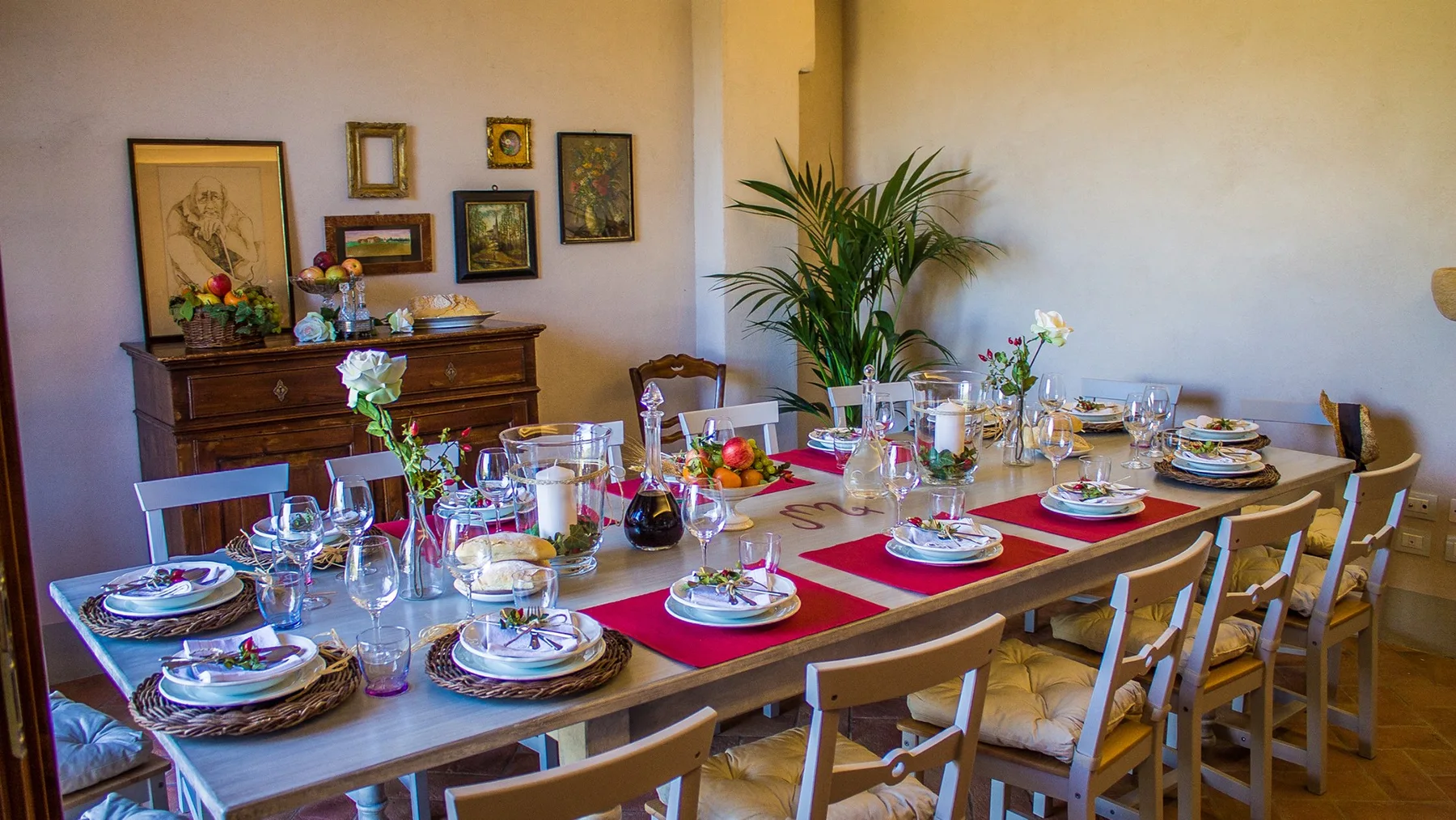 A dining room with a long table set with dishes and flowers.