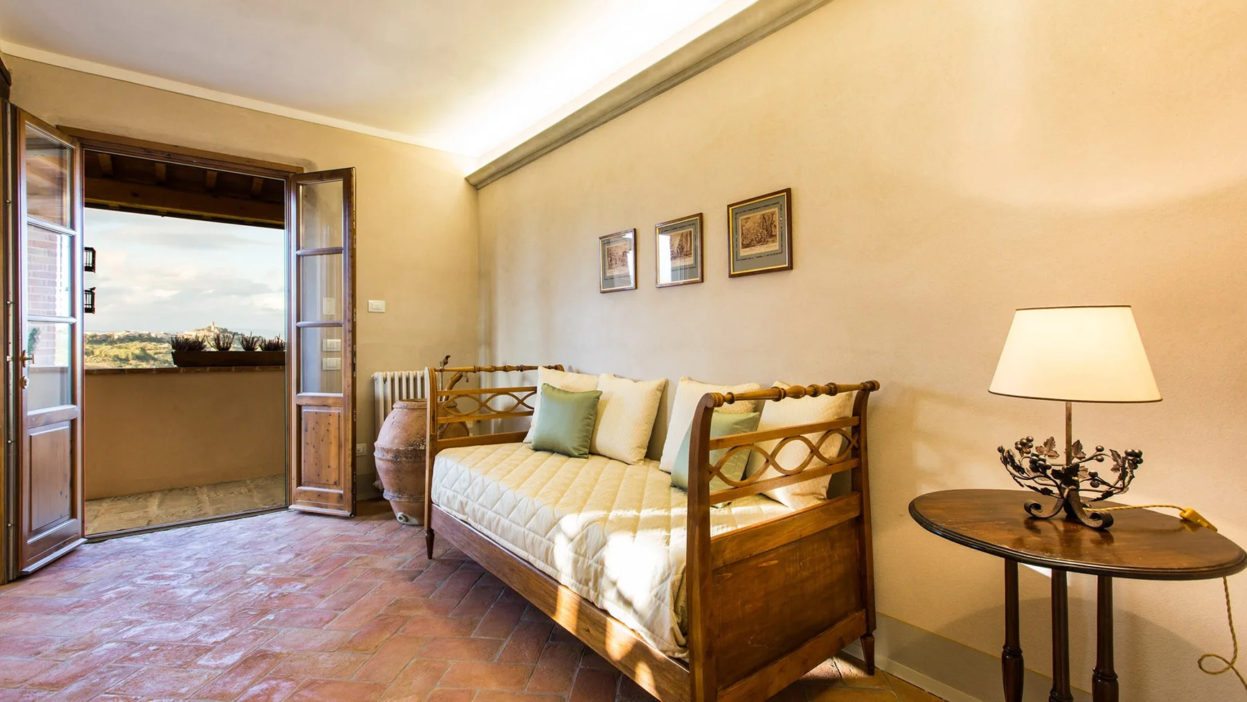 A bedroom with a wooden bed, framed pictures, and an open balcony doorway.
