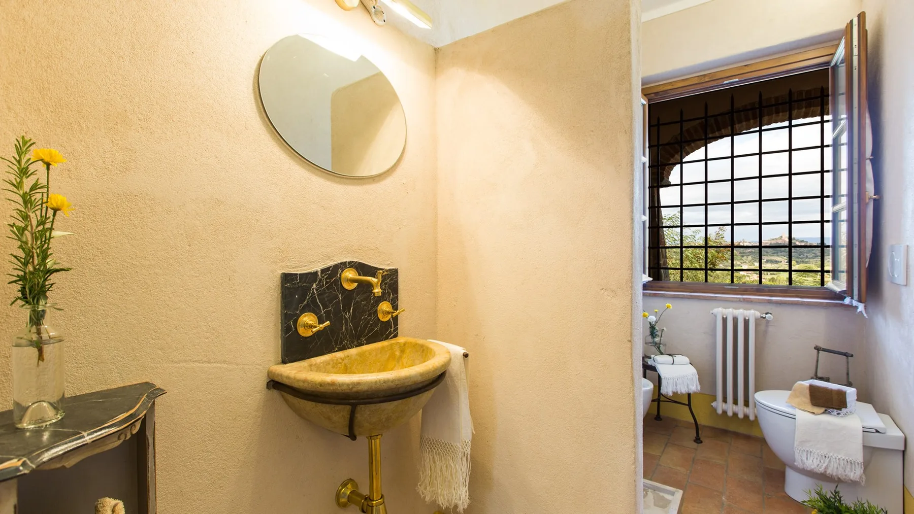 A bathroom with a wall-mounted sink and a window with dark grilles.