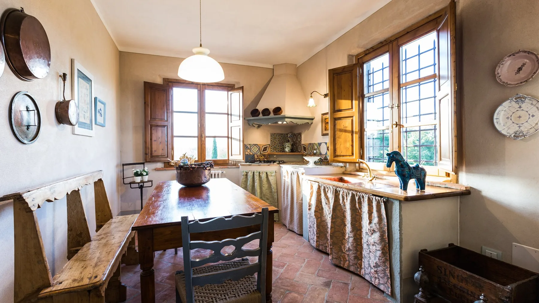 A rustic kitchen with a wooden dining table and large windows.