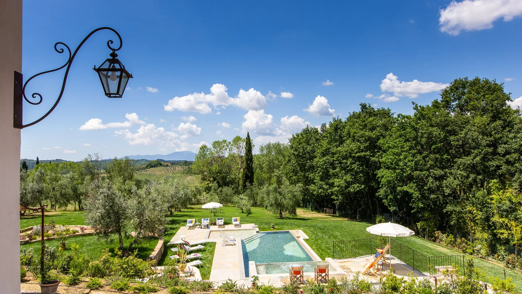 An outdoor swimming pool sits amid a green landscaped garden.