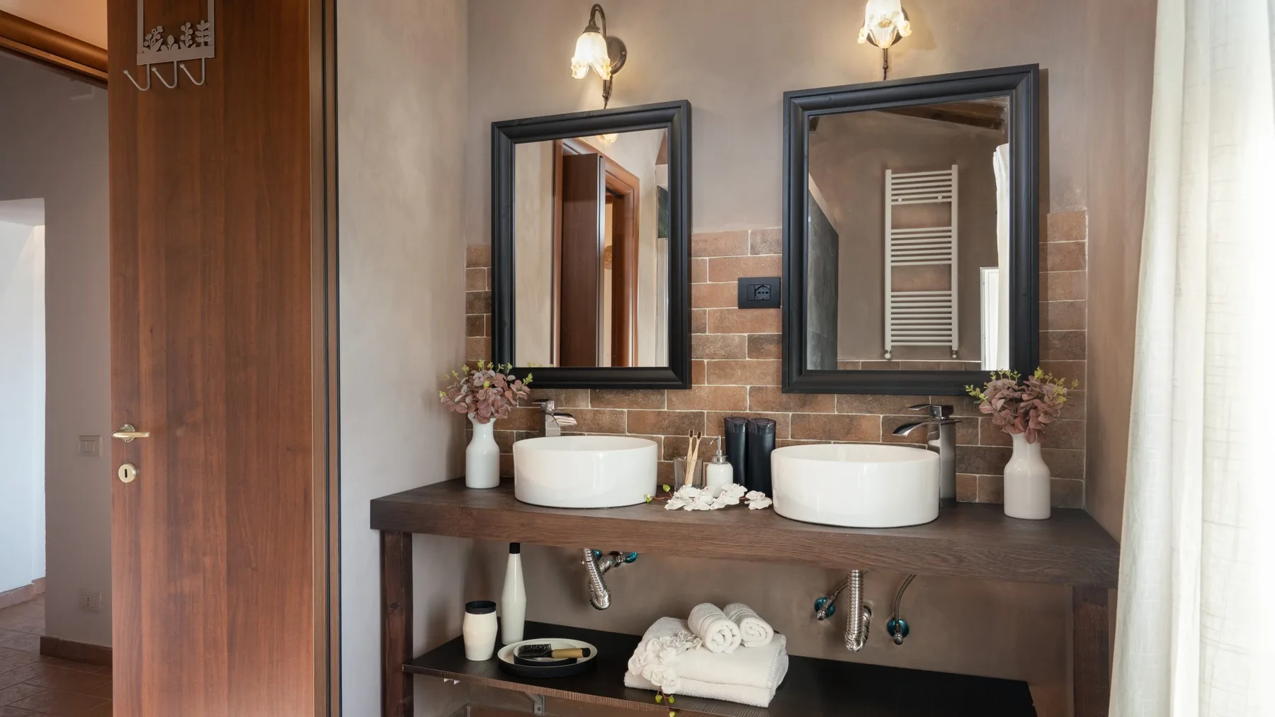 A bathroom vanity with two sinks, mirrors, and folded towels.