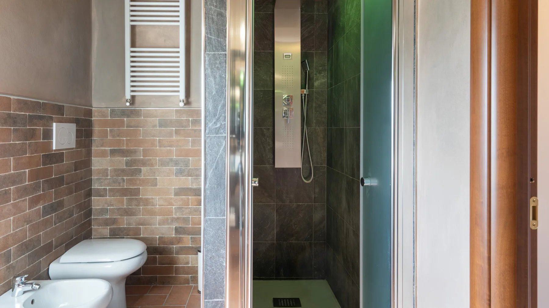 A bathroom with a toilet beside a glass-enclosed shower.