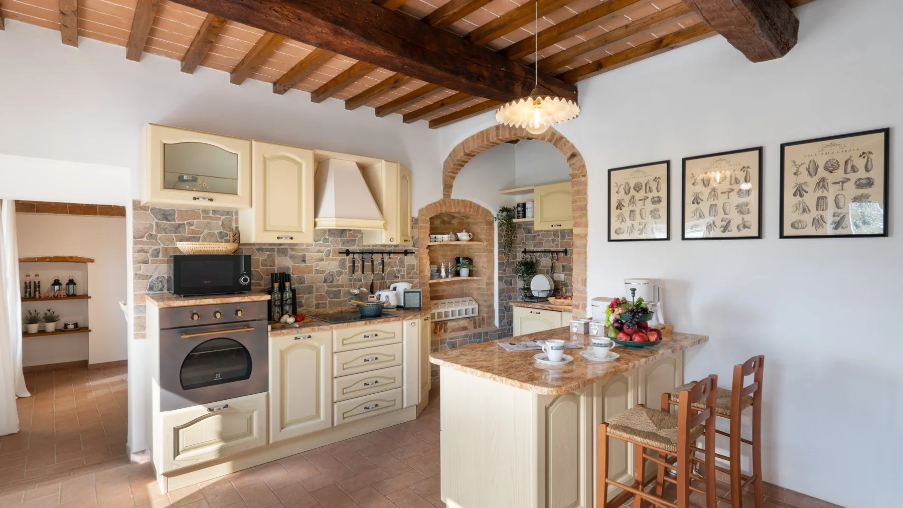 A bright kitchen with a central island and exposed wooden ceiling beams.