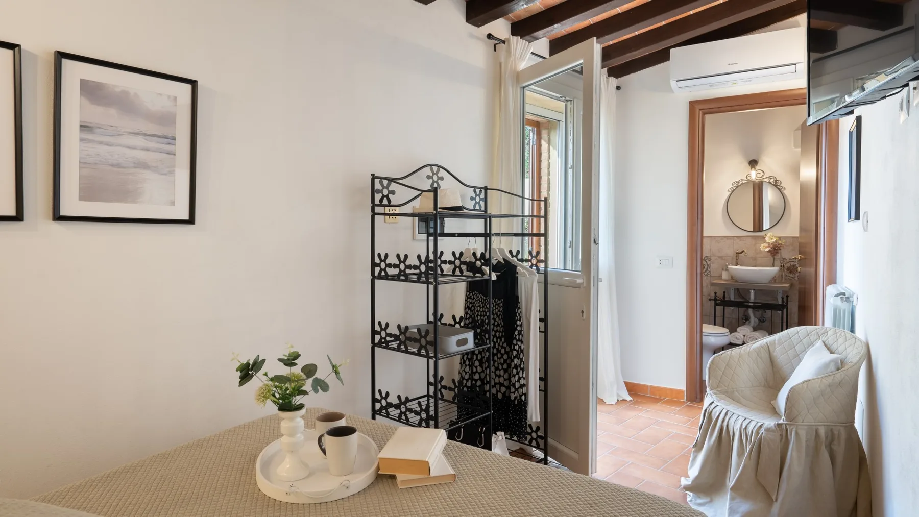 A bedroom with a bed, framed artwork, and an open doorway to a bathroom.