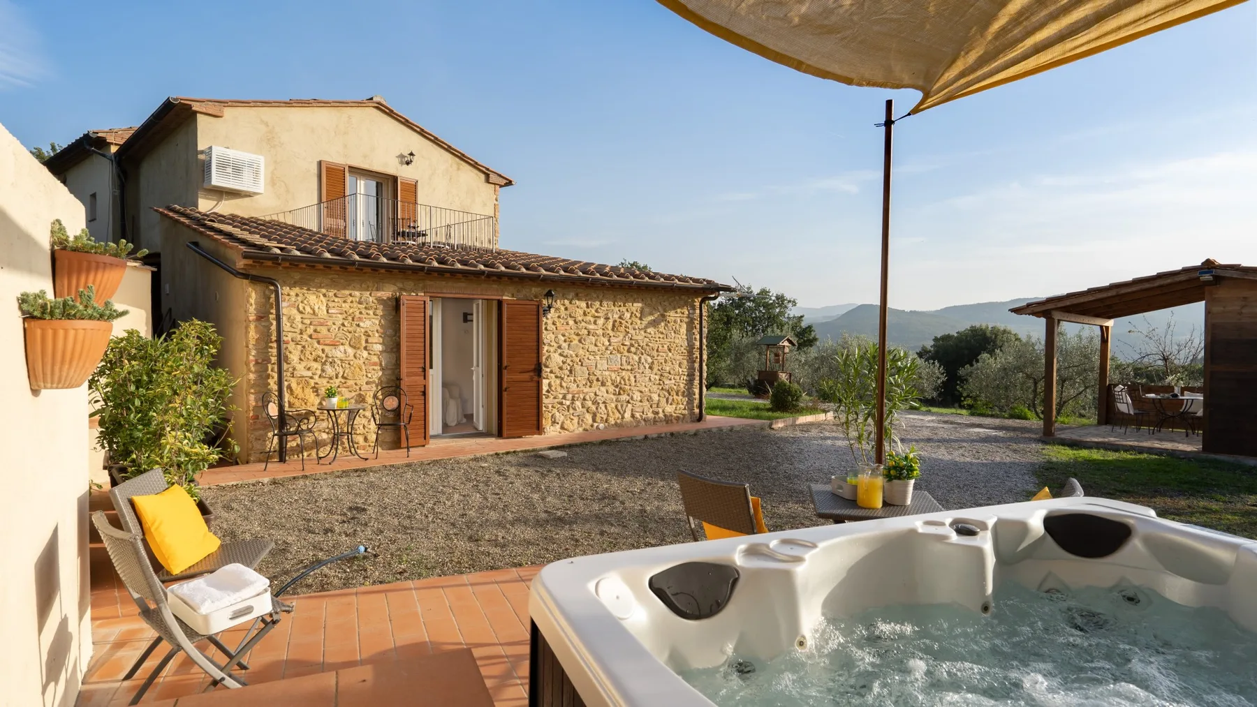 A stone house and courtyard with a bubbling hot tub in the foreground.