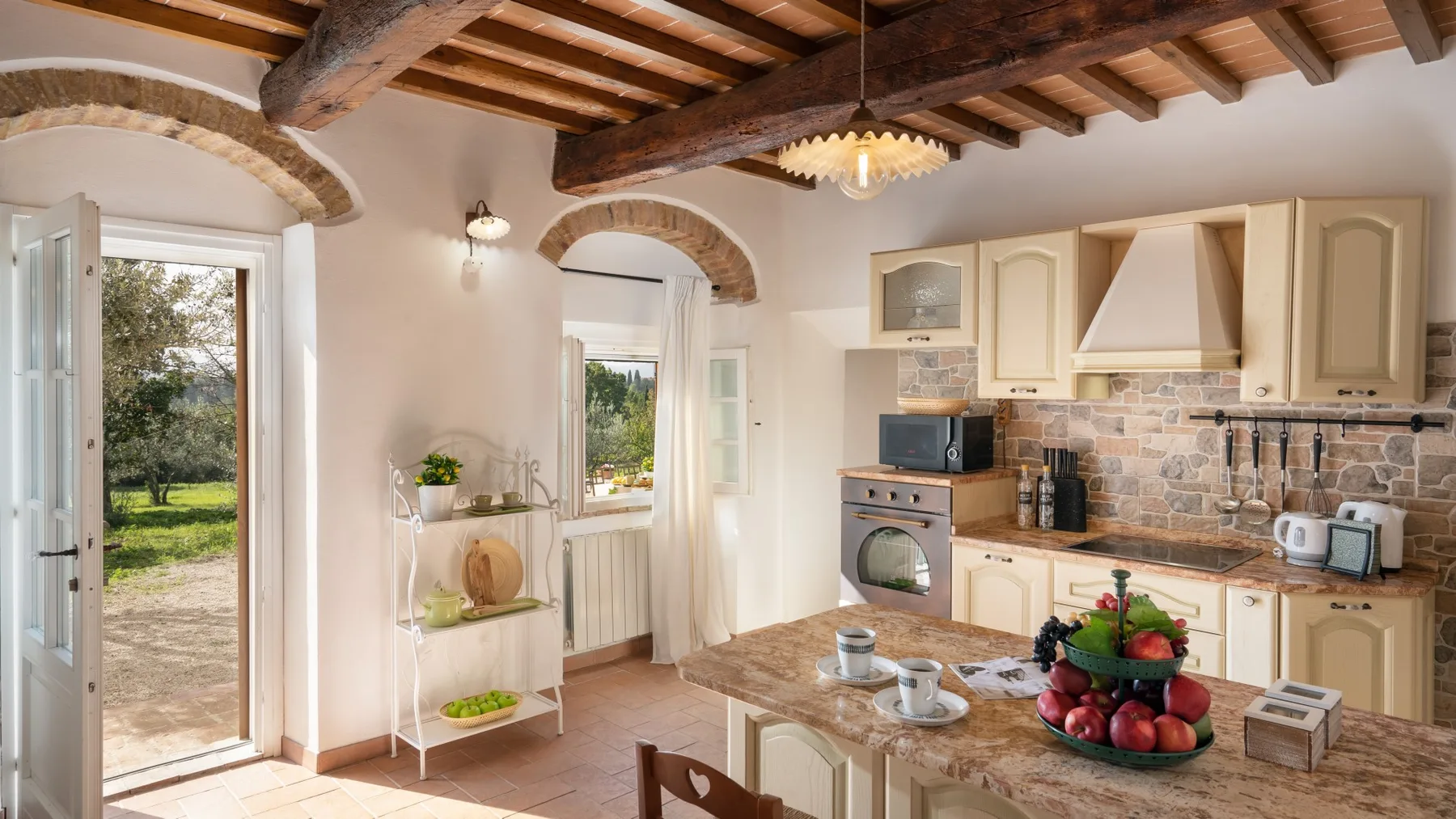 A rustic kitchen with wooden ceiling beams and a central island.