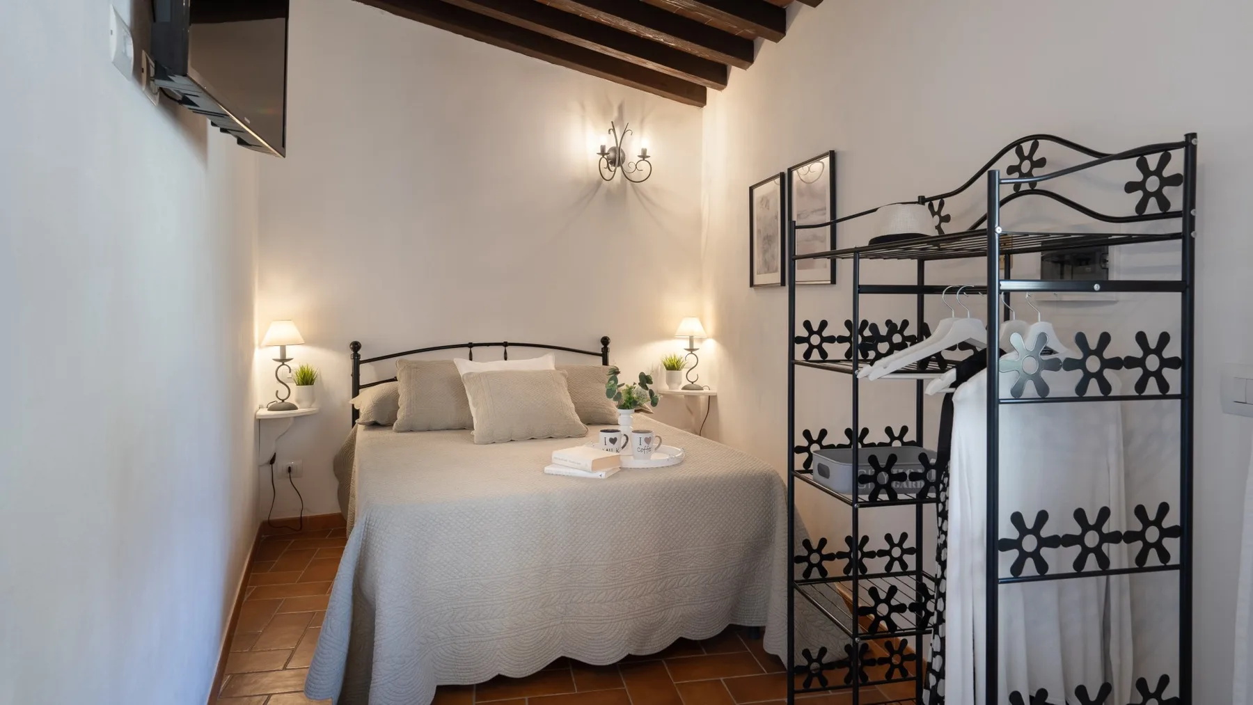 A bedroom with a neatly made bed and a decorative black metal divider.
