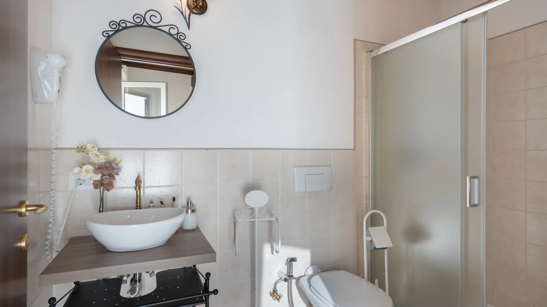 A bathroom vanity with a vessel sink sits beside a glass shower.