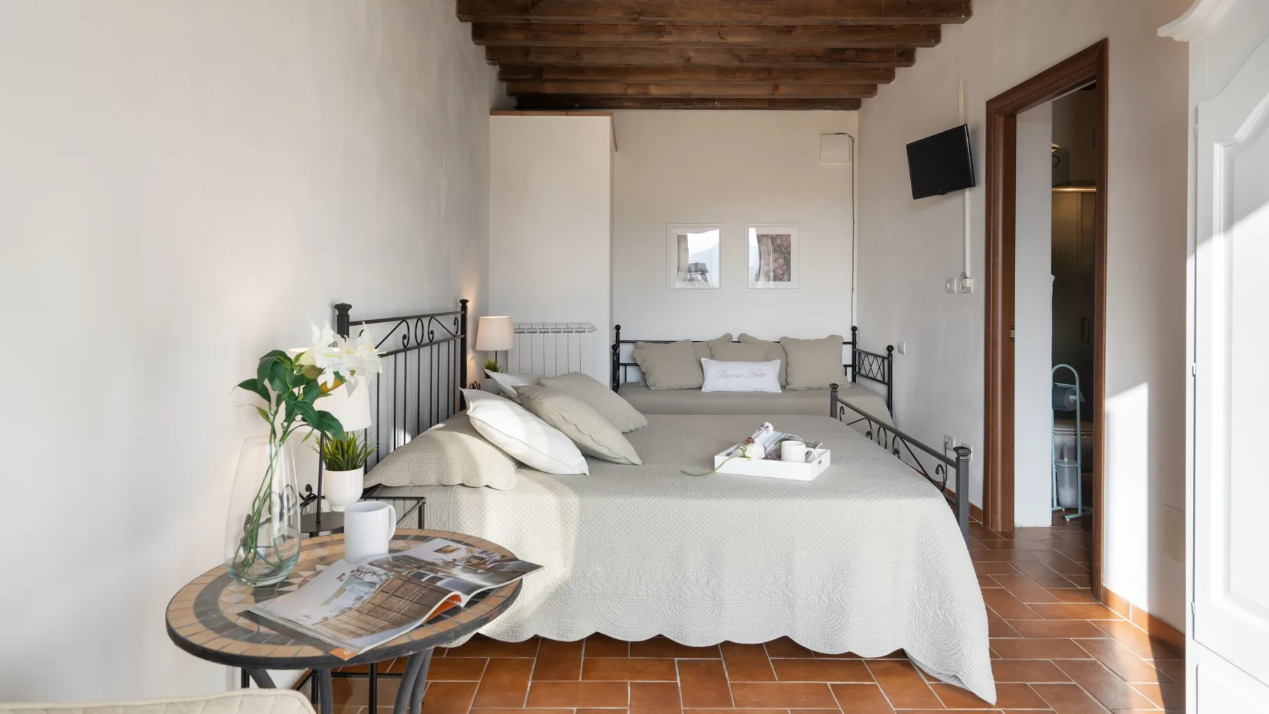 A bedroom with a bed, bedside table, and exposed wooden ceiling beams.