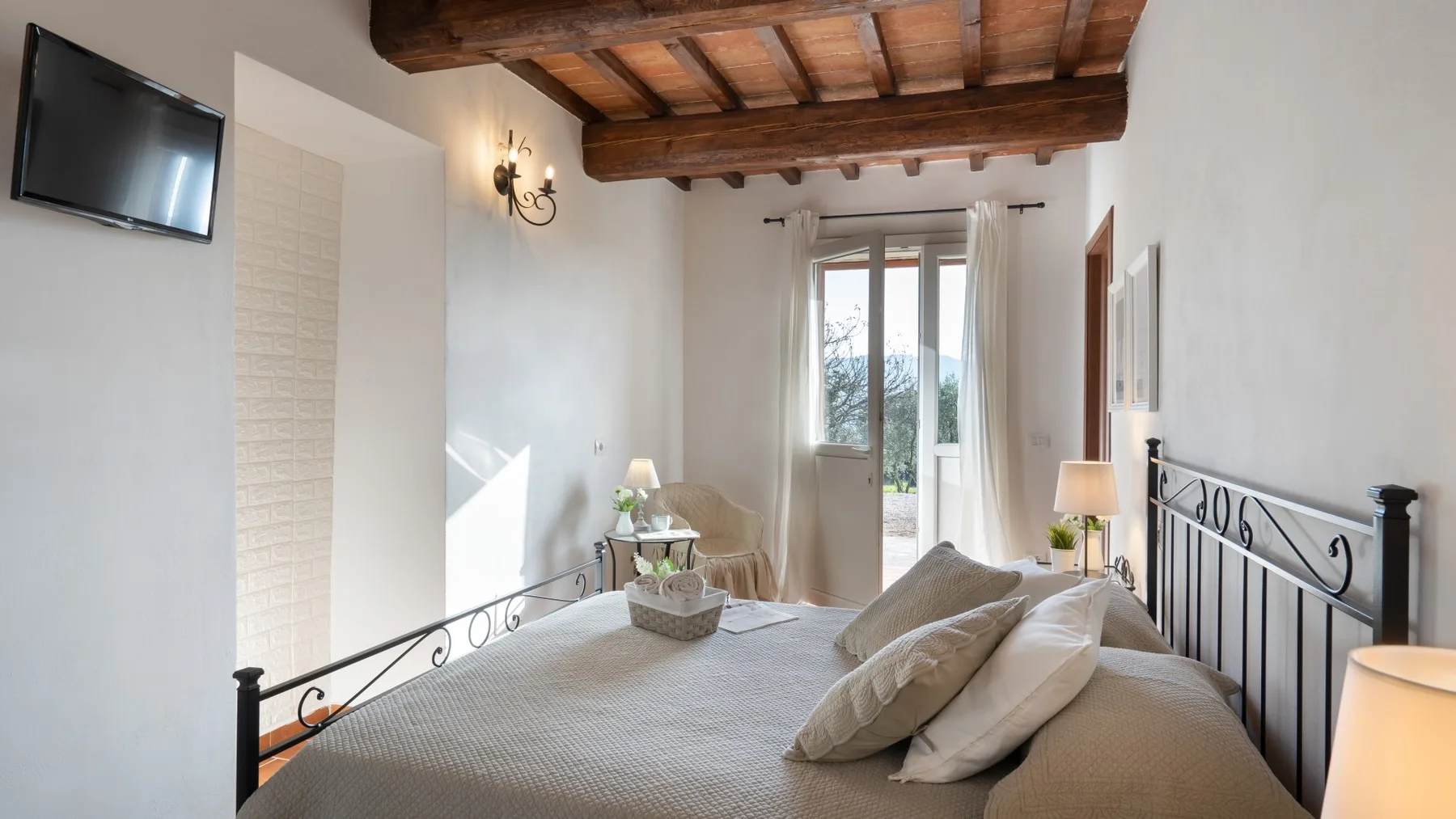 A bedroom with a bed, bedside lamps, and a window with curtains.
