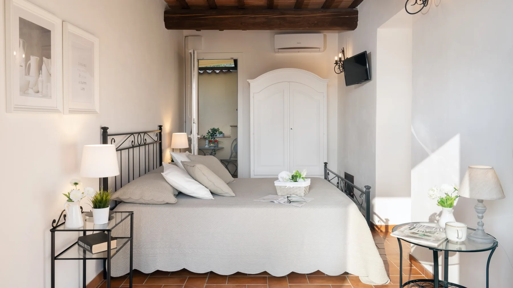 A bedroom with a bed, bedside tables, and a television mounted on the wall.