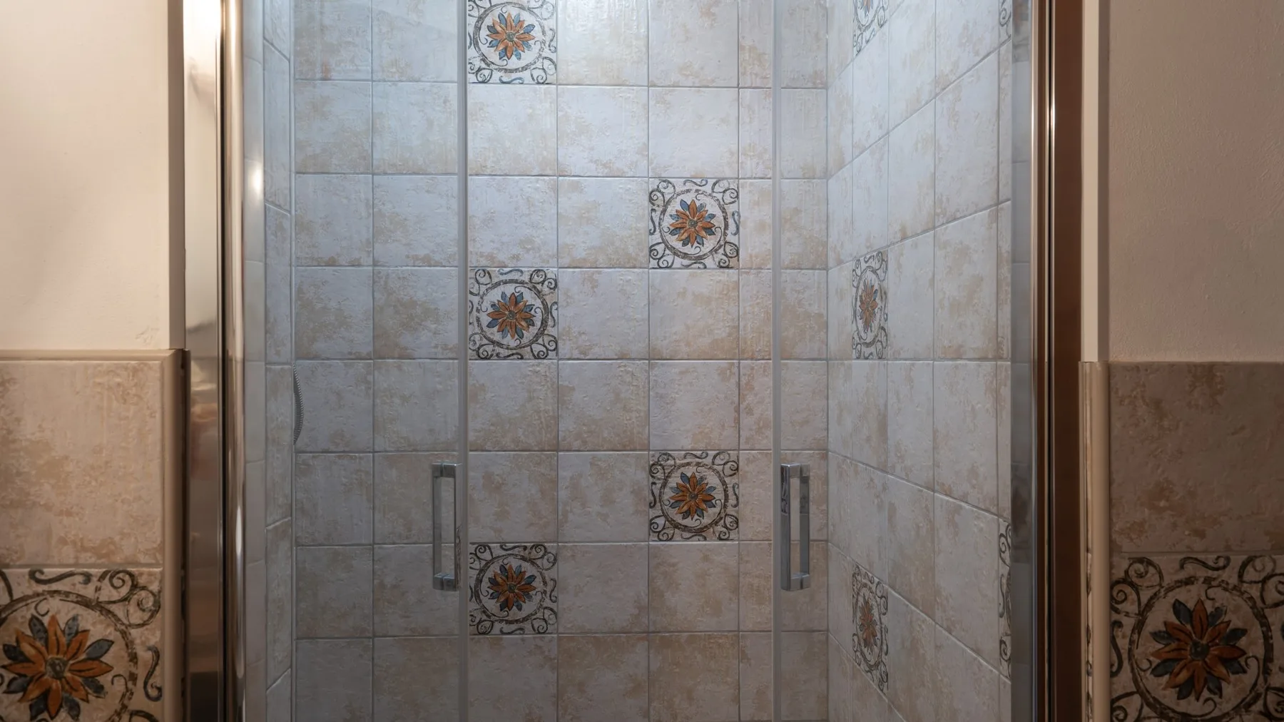 A tiled shower with decorative floral accents.