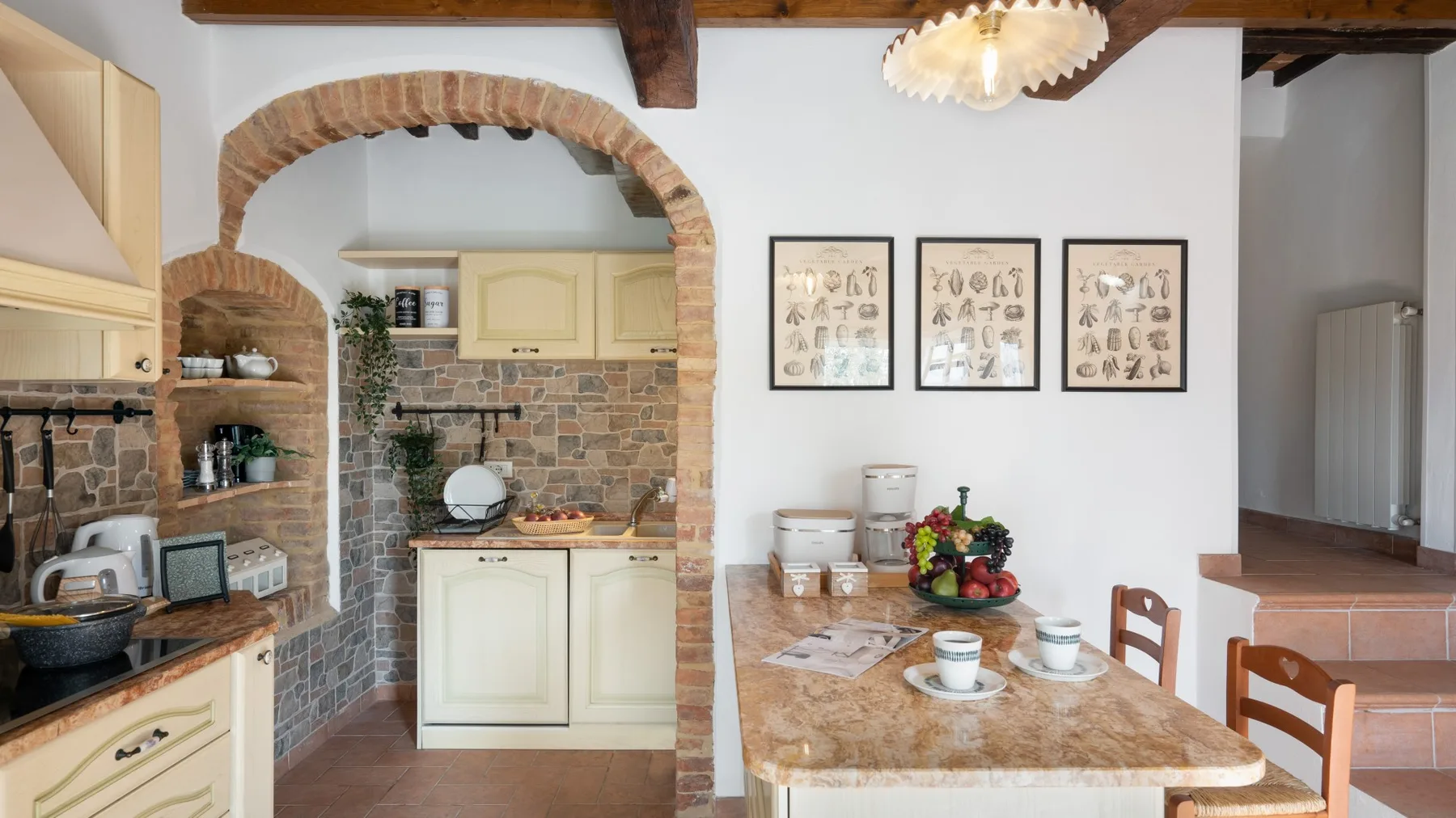 A rustic kitchen and dining area with a stone-topped table and brick archway.