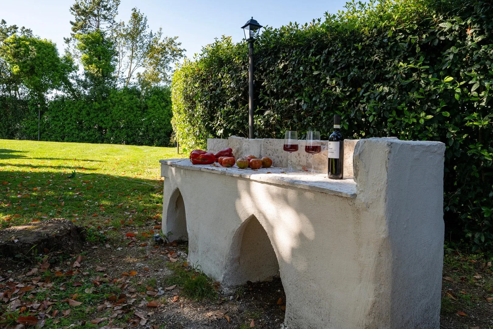A garden patio with a built-in stone bench and drinks set on top.