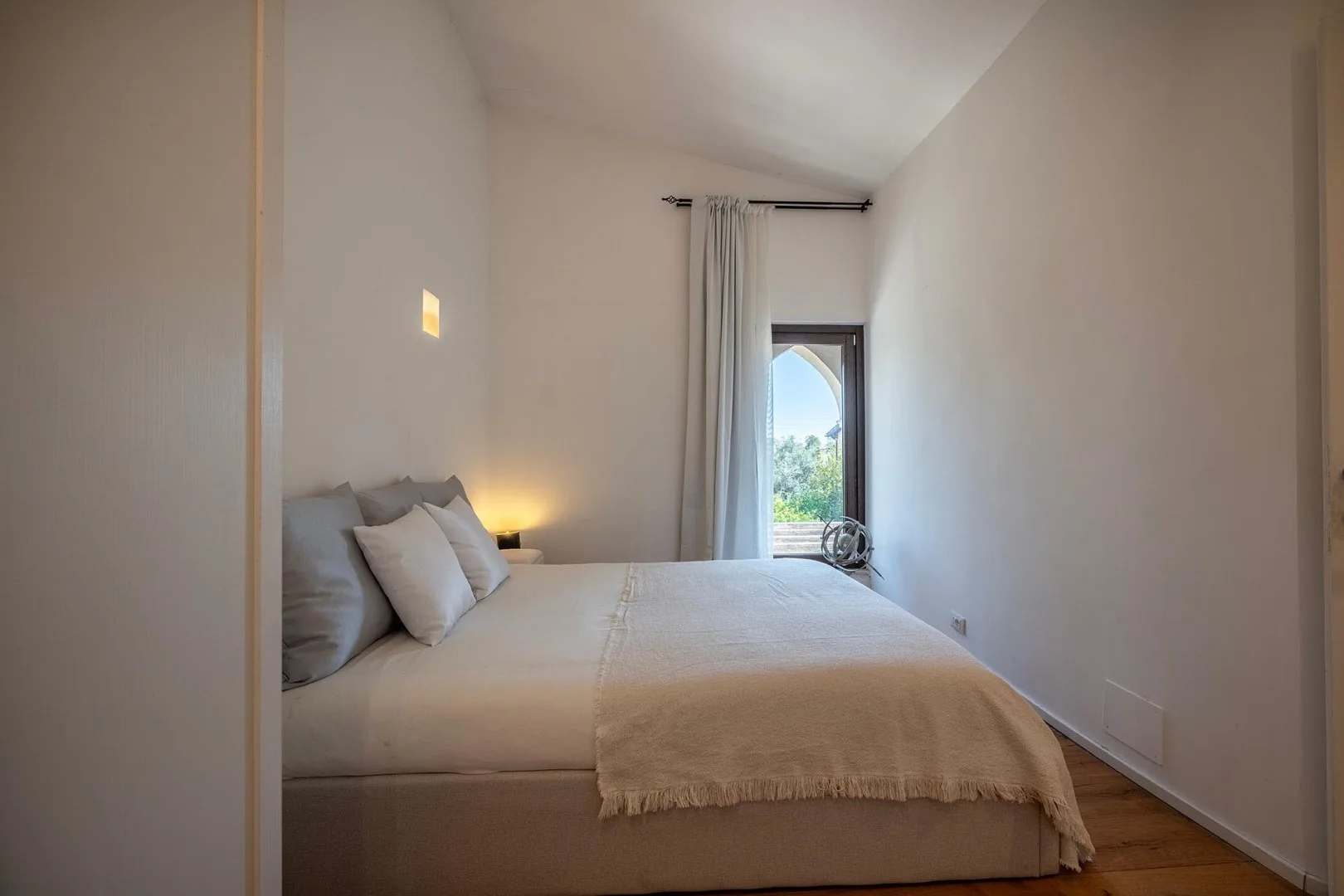 A bedroom with a bed beside a narrow window and curtain.