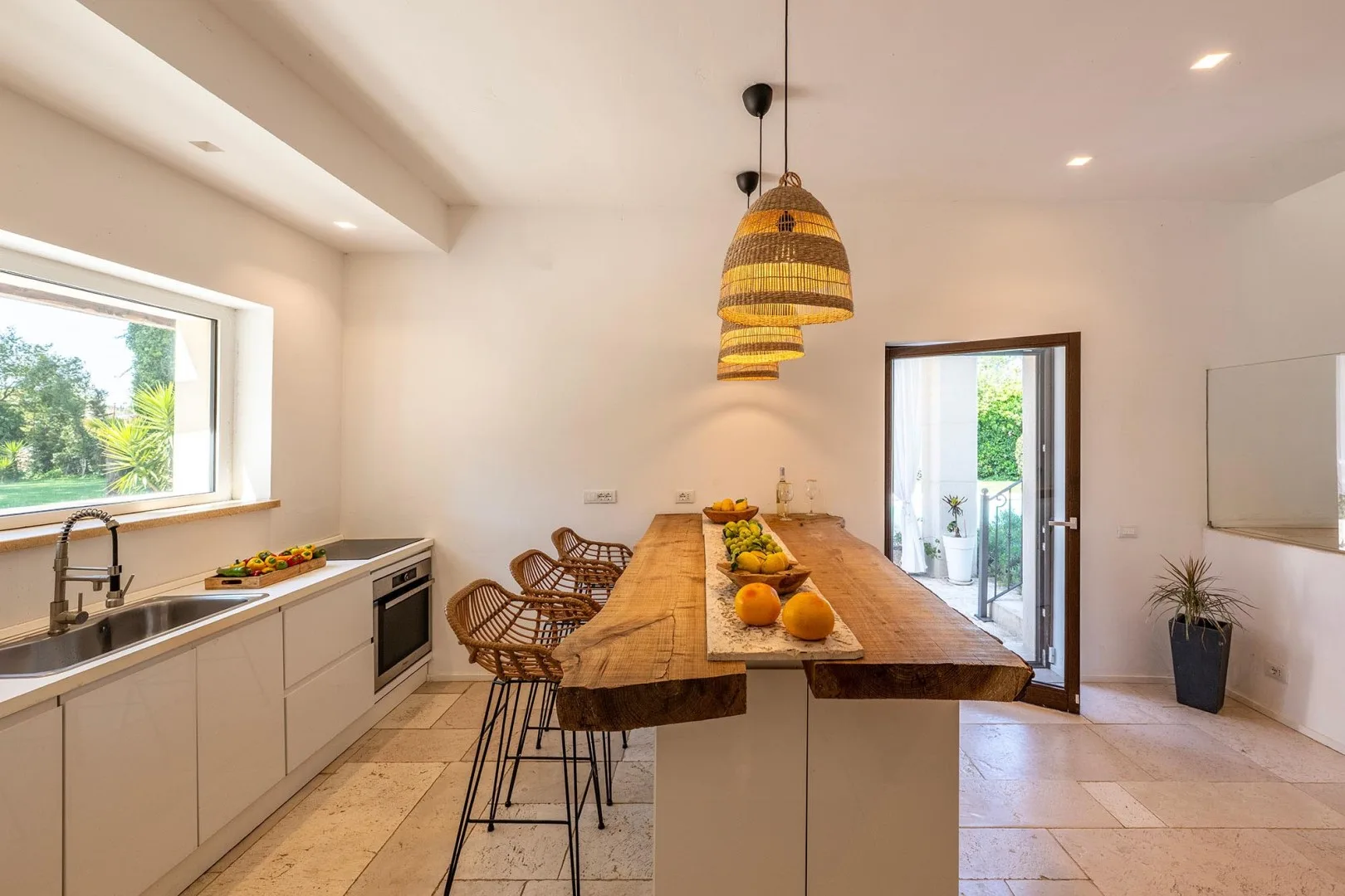 A bright kitchen and dining area with a long wooden table and hanging lights.