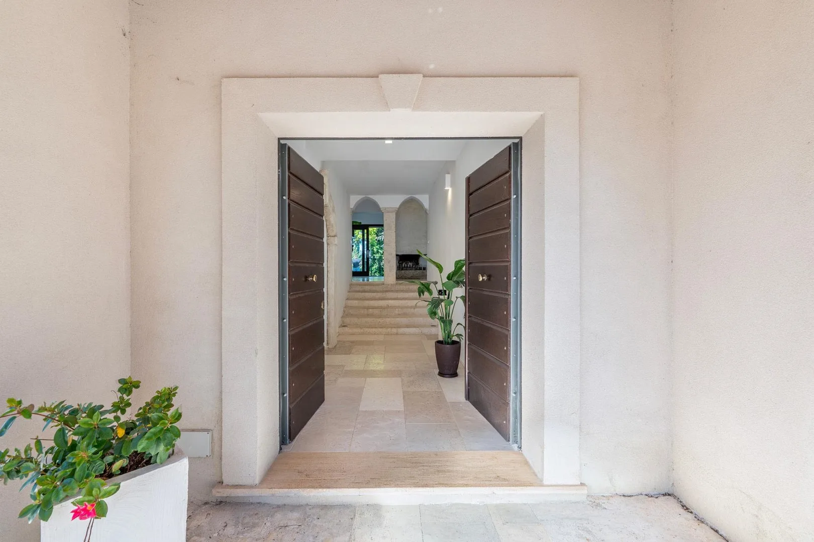 An open entryway leads into a bright interior with plants.