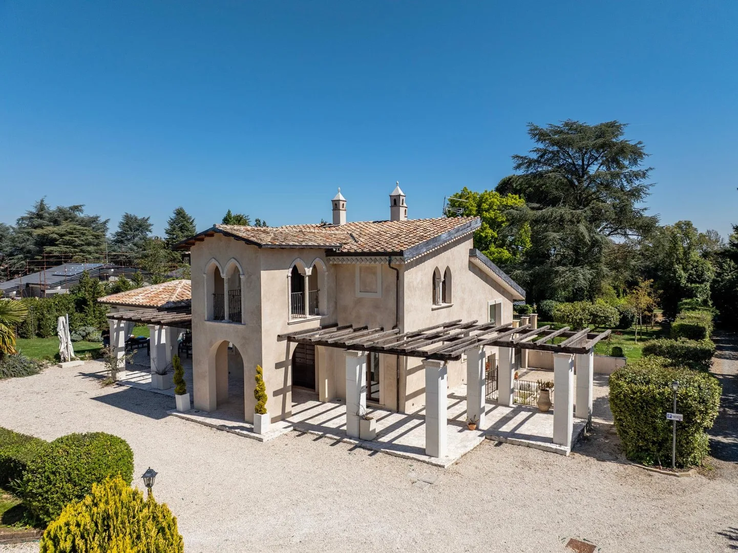 A stucco house with a tiled roof and an open pergola in the courtyard.