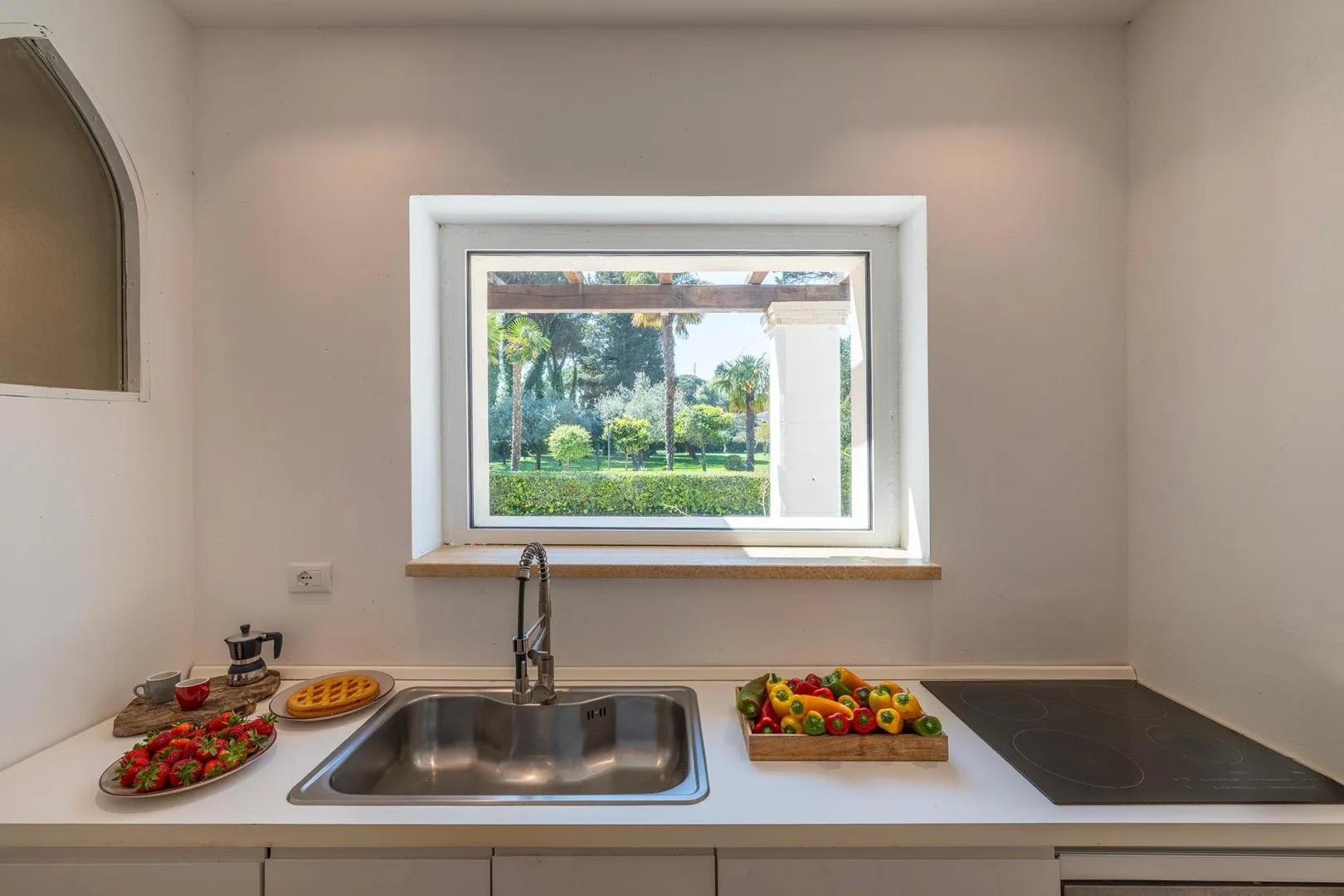 A kitchen counter with a sink and fresh produce beneath a window.