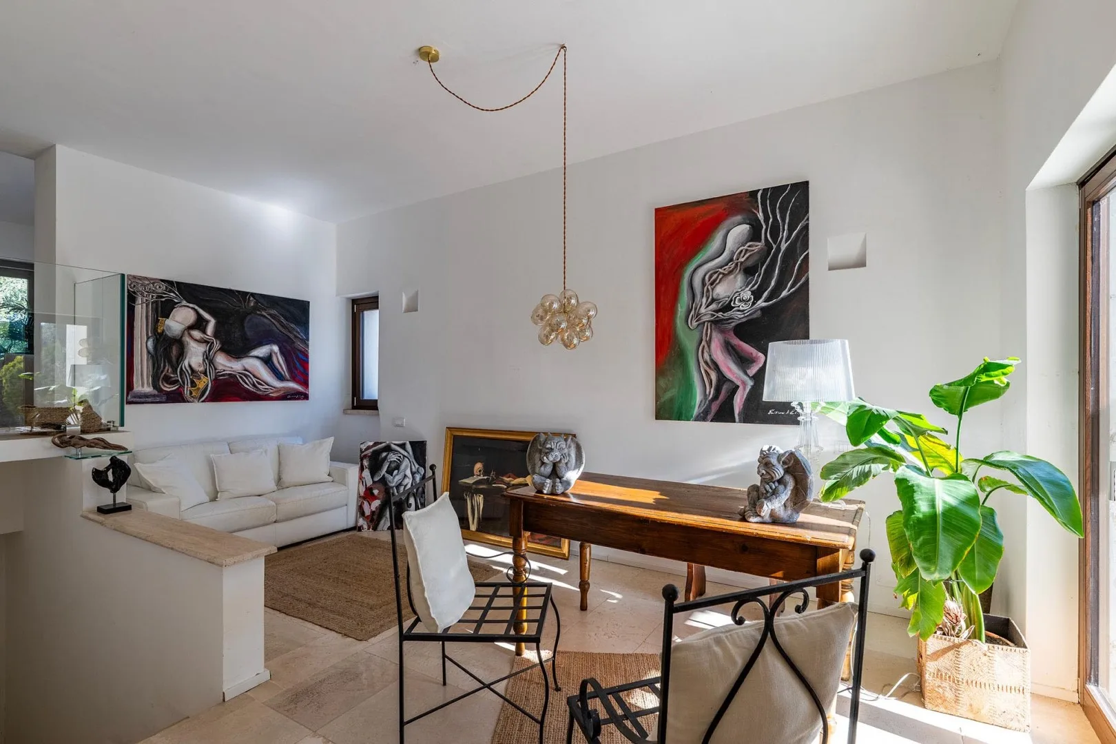 A bright living and dining area with a wooden table, seating, and large artwork.