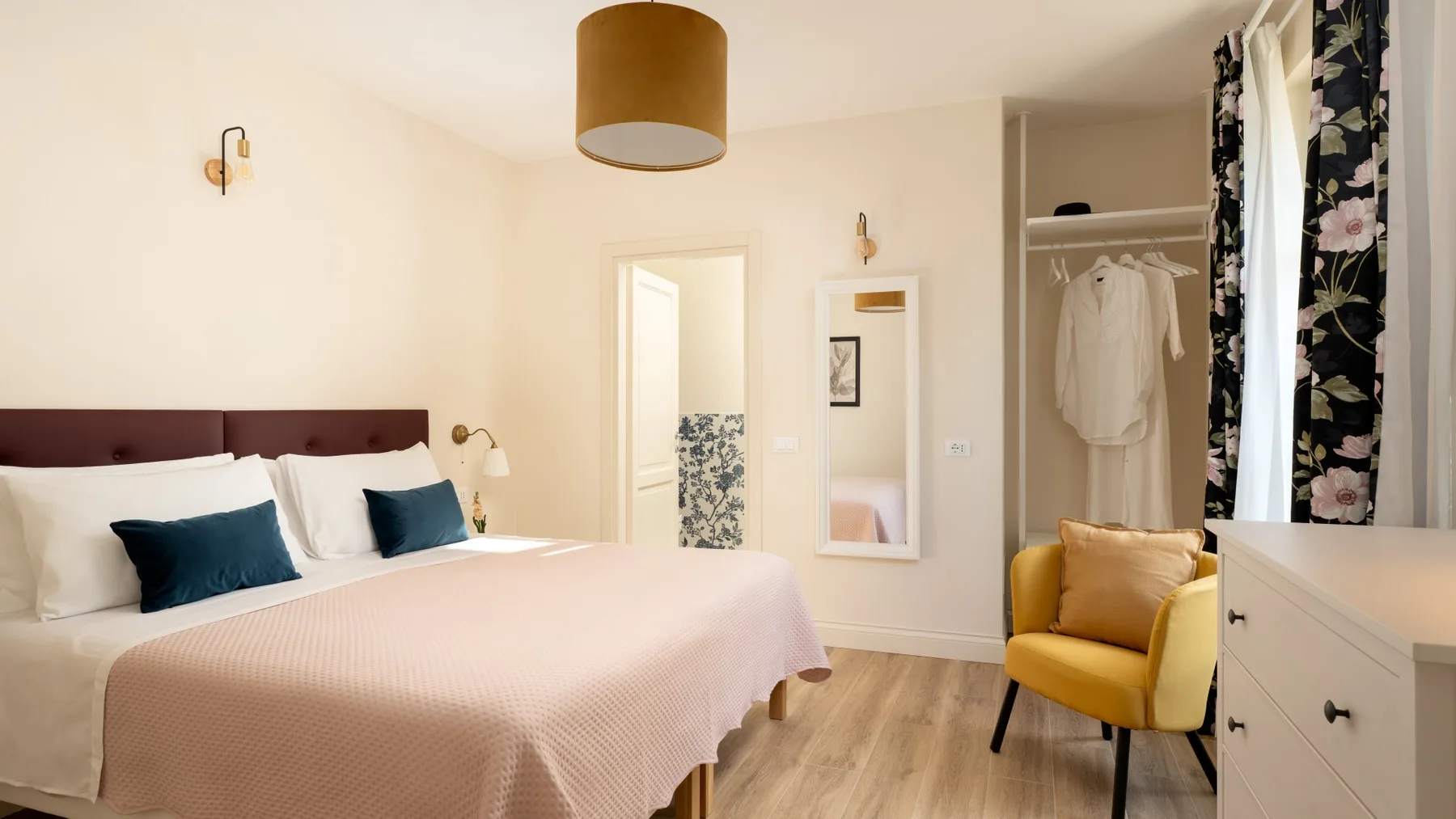 Un dormitorio con una cama, un armario abierto y un sillón amarillo.