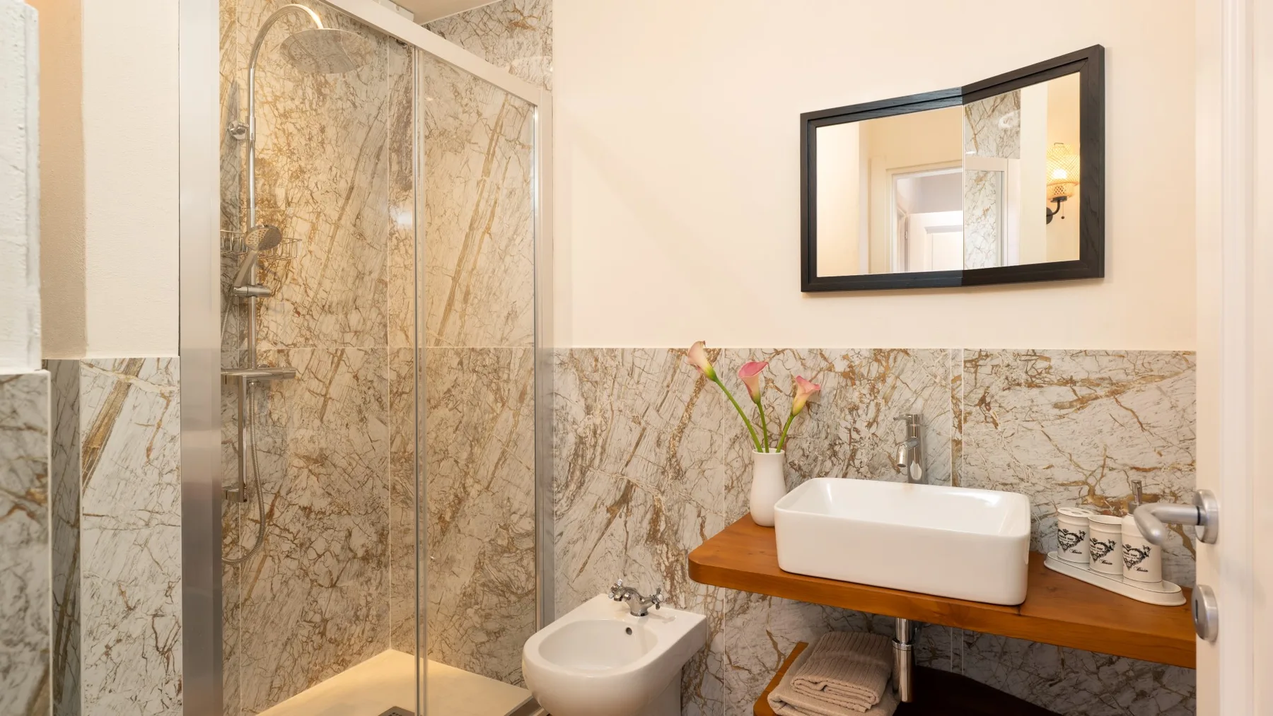Un baño con ducha de vidrio, lavabo sobre encimera y espejo de pared.