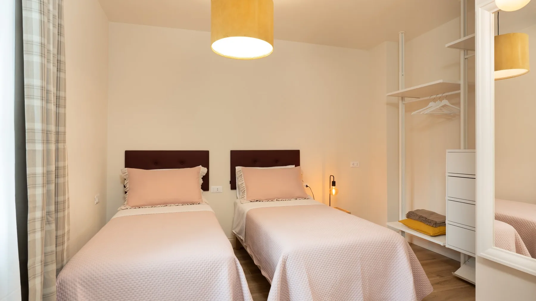 Un dormitorio con dos camas y espacio de almacenamiento abierto para ropa.