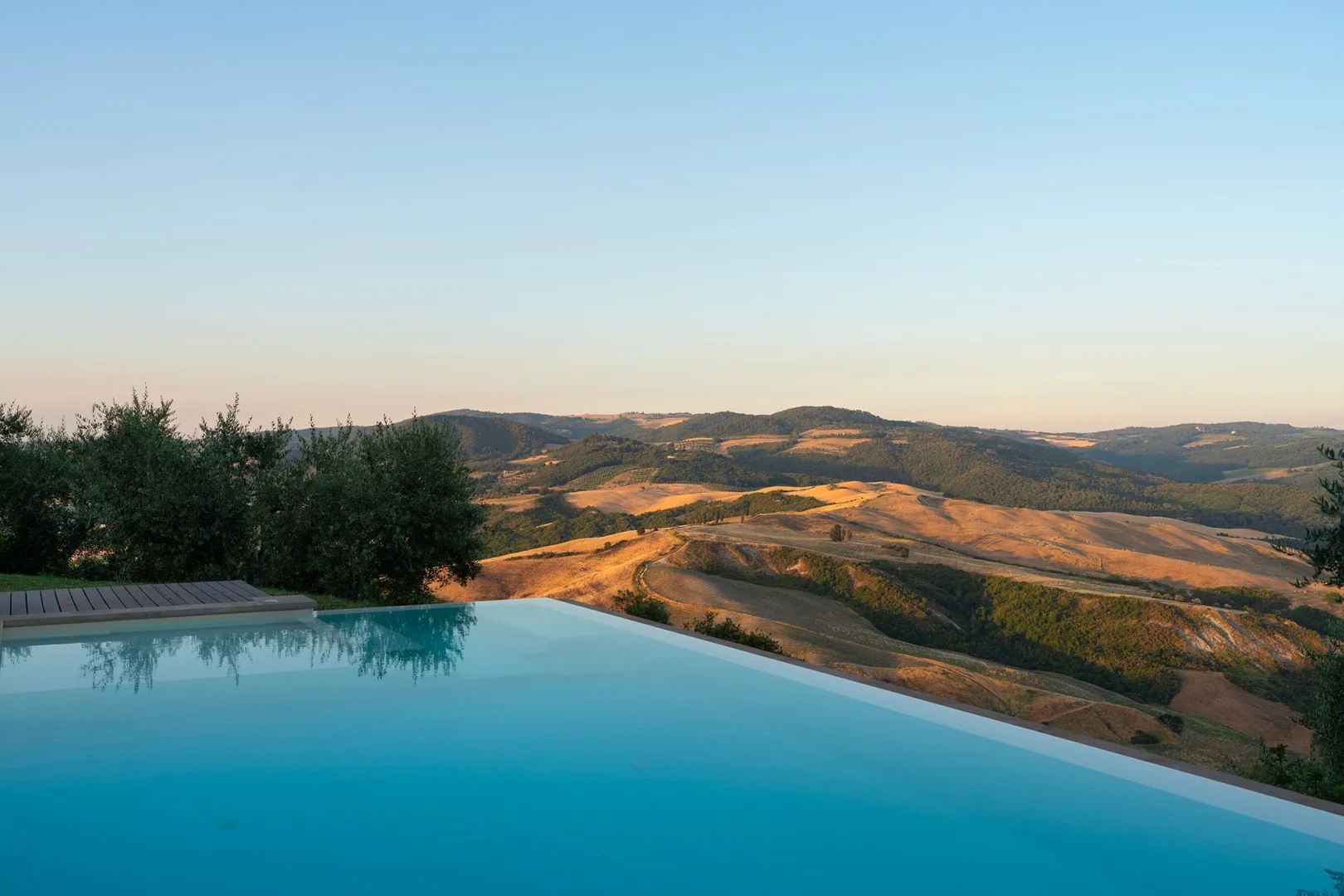 Una piscina al aire libre ofrece vistas de colinas onduladas al atardecer.