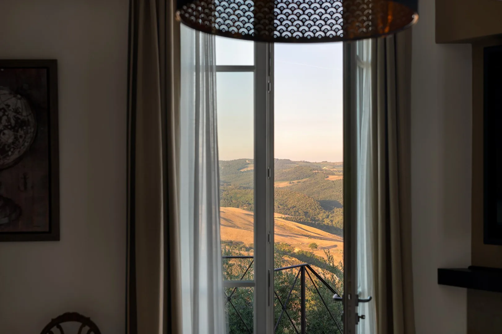 Una habitación se abre a un balcón con vistas a colinas onduladas.