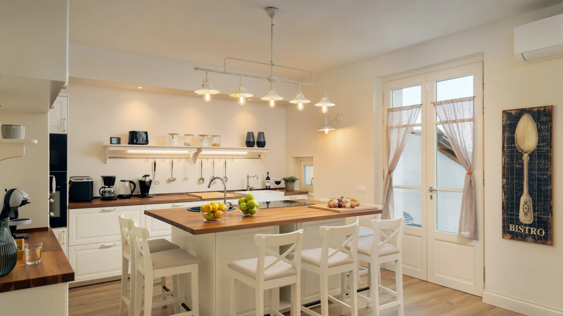 Una cocina luminosa con una isla central y varios taburetes.