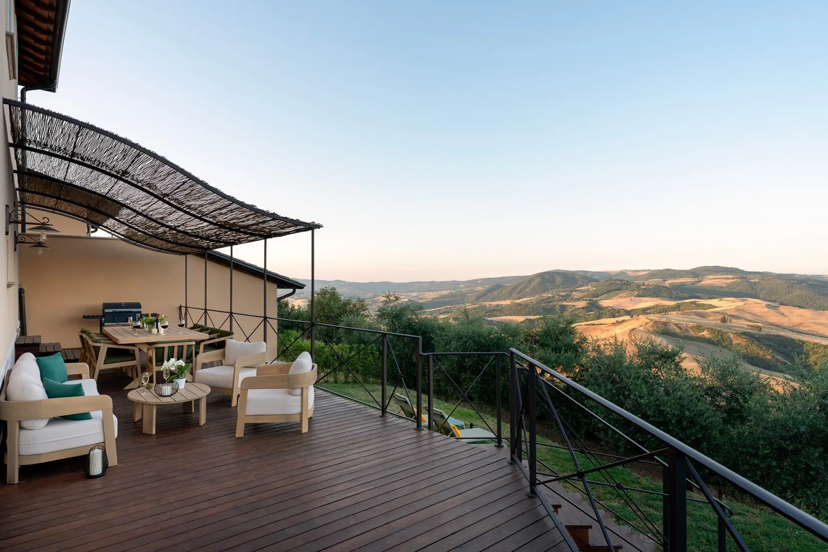 Una terraza amueblada al aire libre da a un amplio paisaje de colinas y valles.