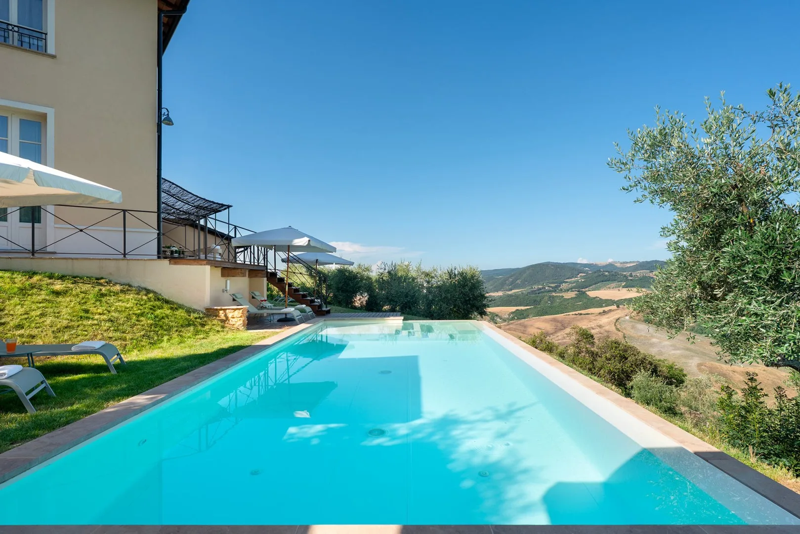 Una piscina al aire libre junto a una casa, con colinas visibles a lo lejos.