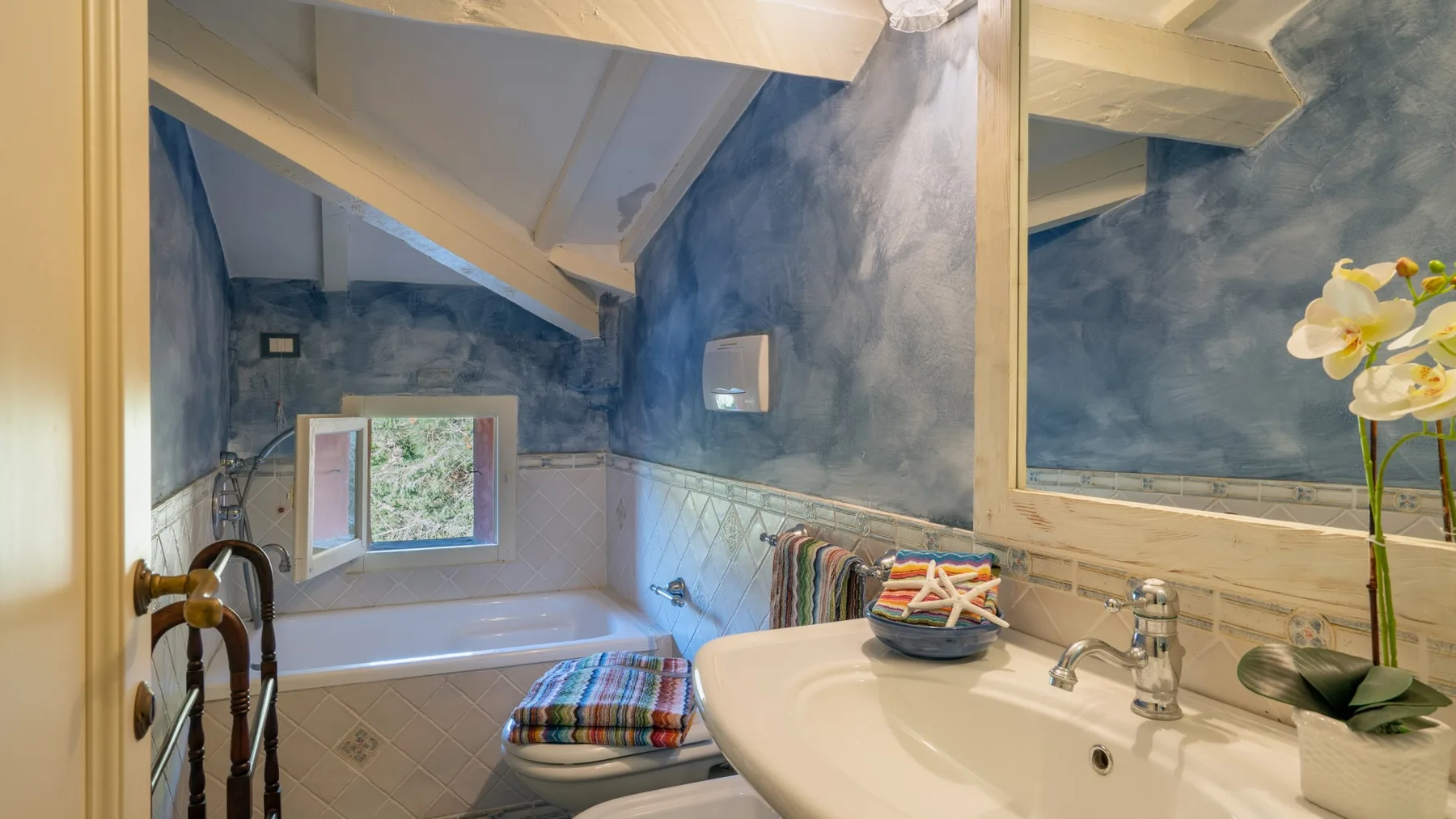 A bathroom with a bathtub and sink beneath a sloped ceiling.
