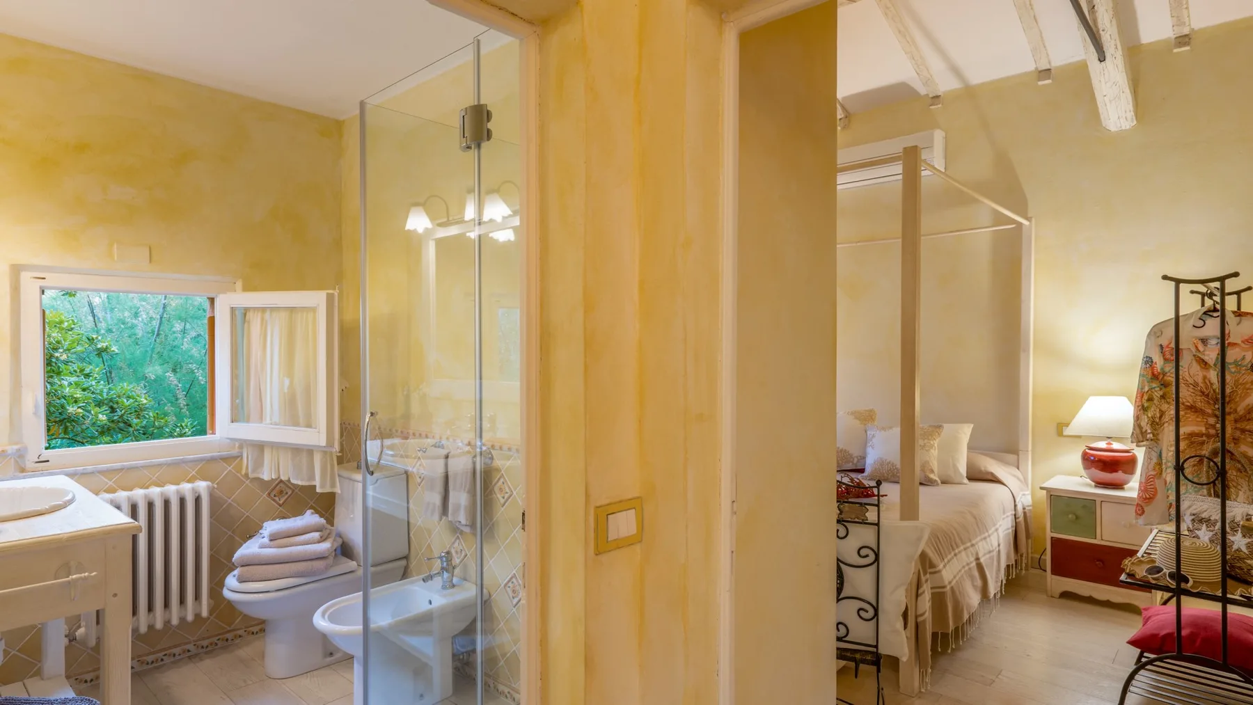 A bedroom and adjoining bathroom are visible, with a bed and glass shower enclosure.
