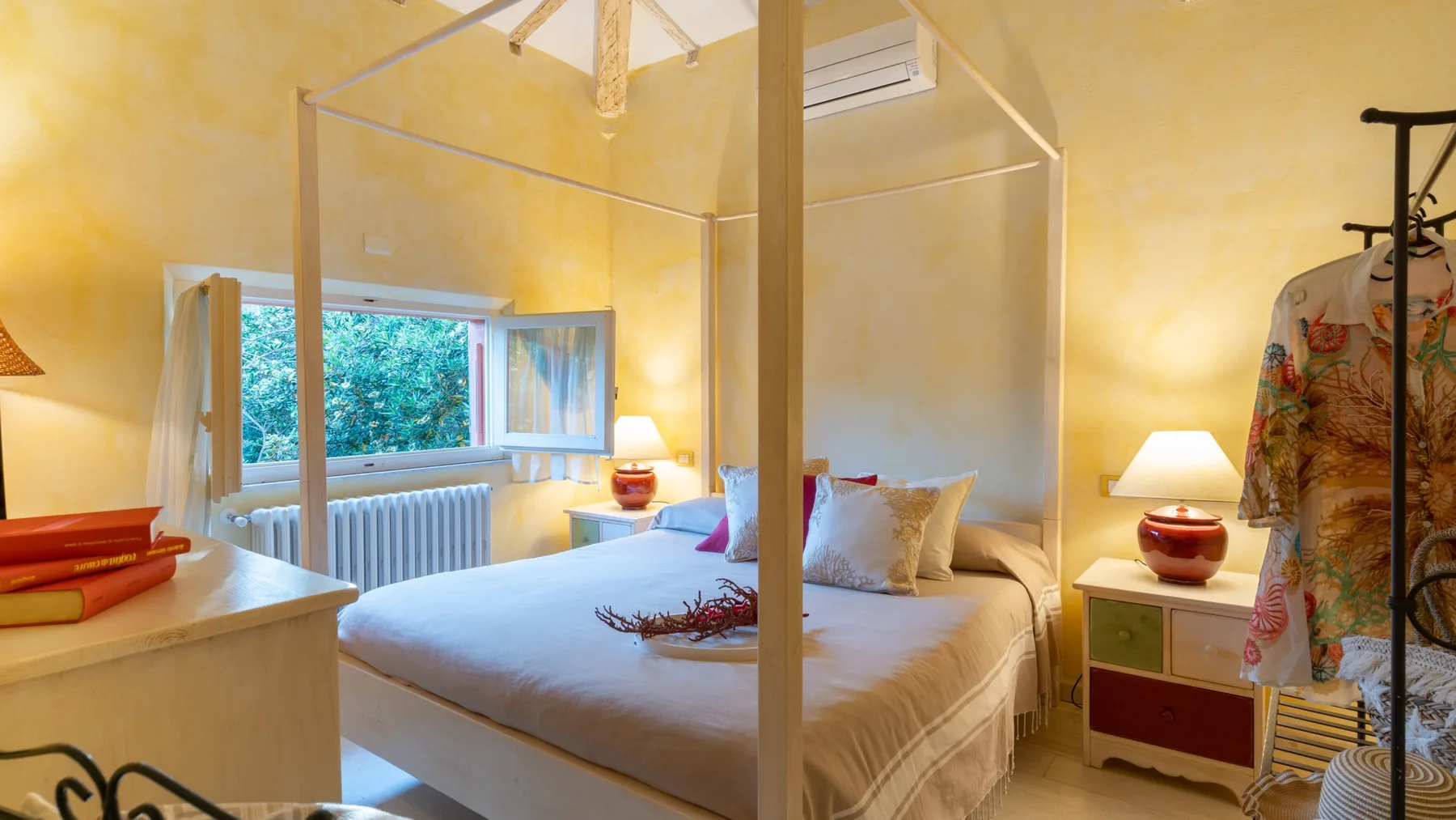 A bedroom with a canopy bed, open window, and bedside lamps.